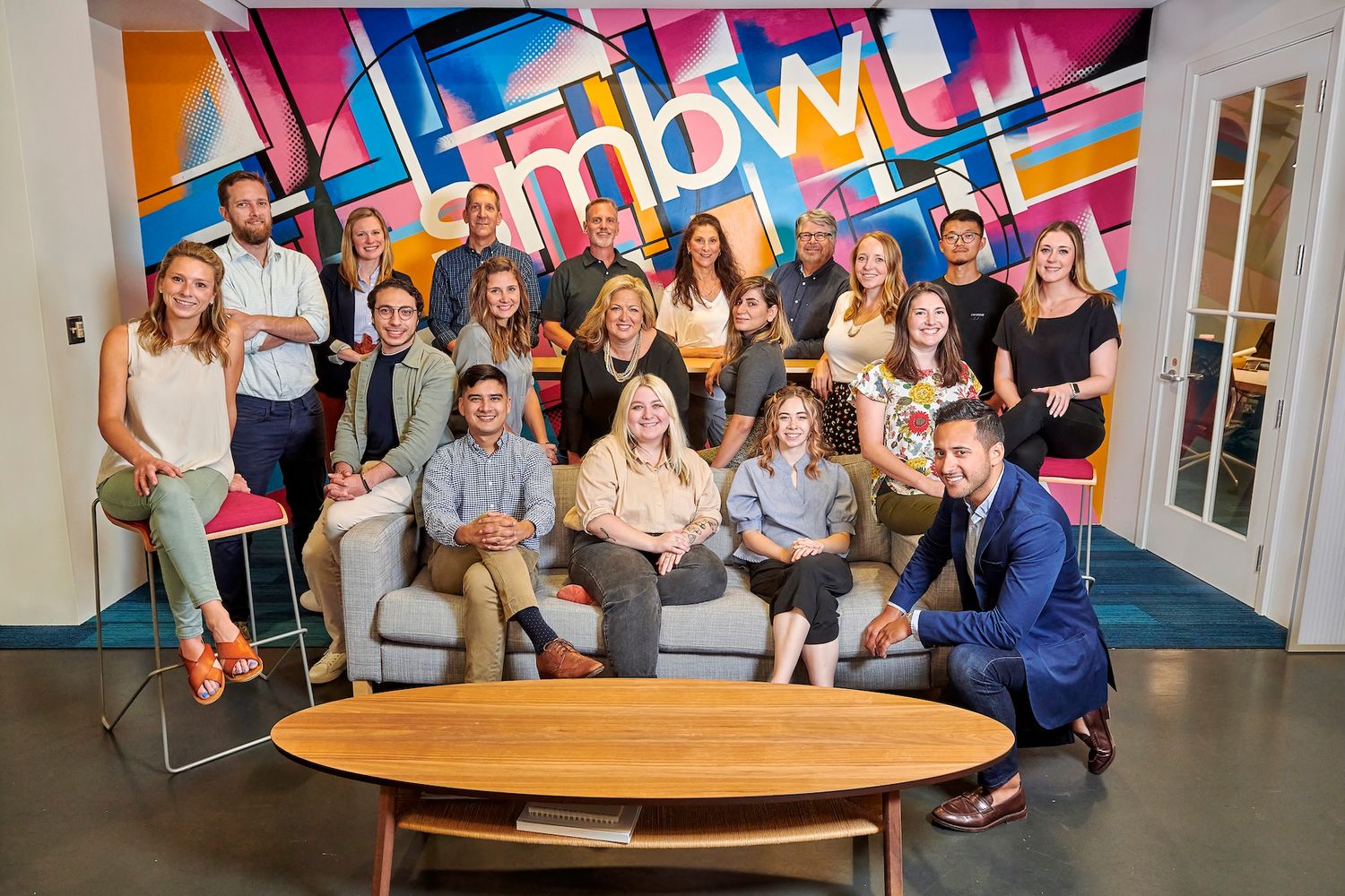 Diverse team of professionals posing together in colorful modern office.