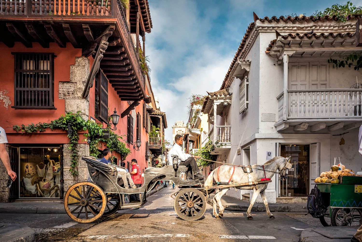 Horse-drawn carriages on a colorful colonial street in Cartagena, Colombia.