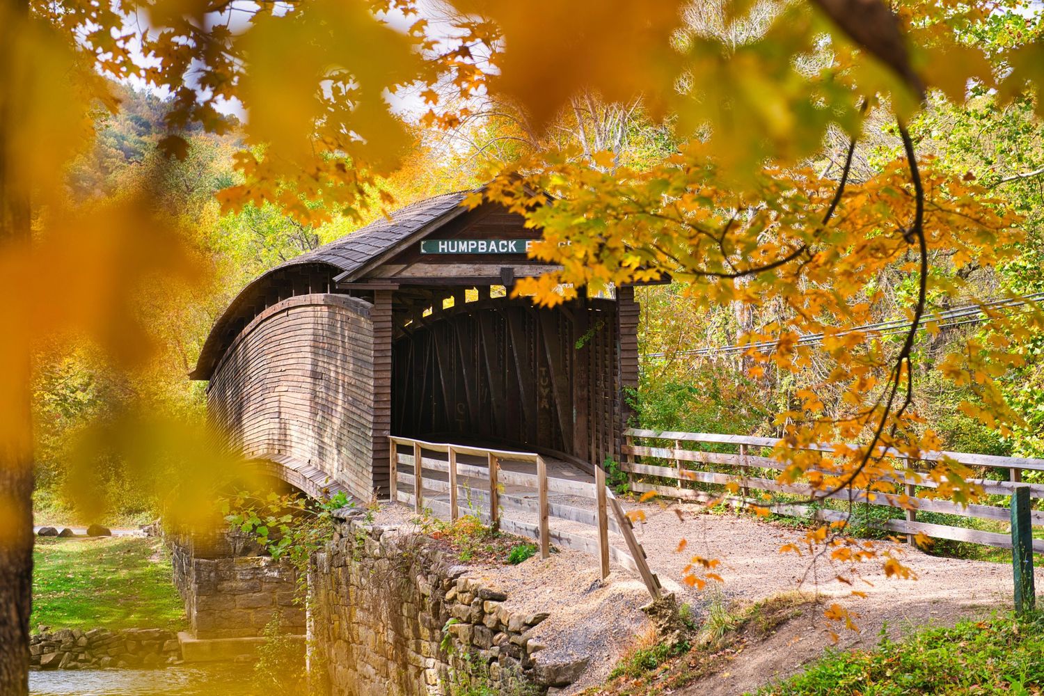 Historic Humpback covered bridge surrounded by brilliant fall foliage in Covington, Virginia.