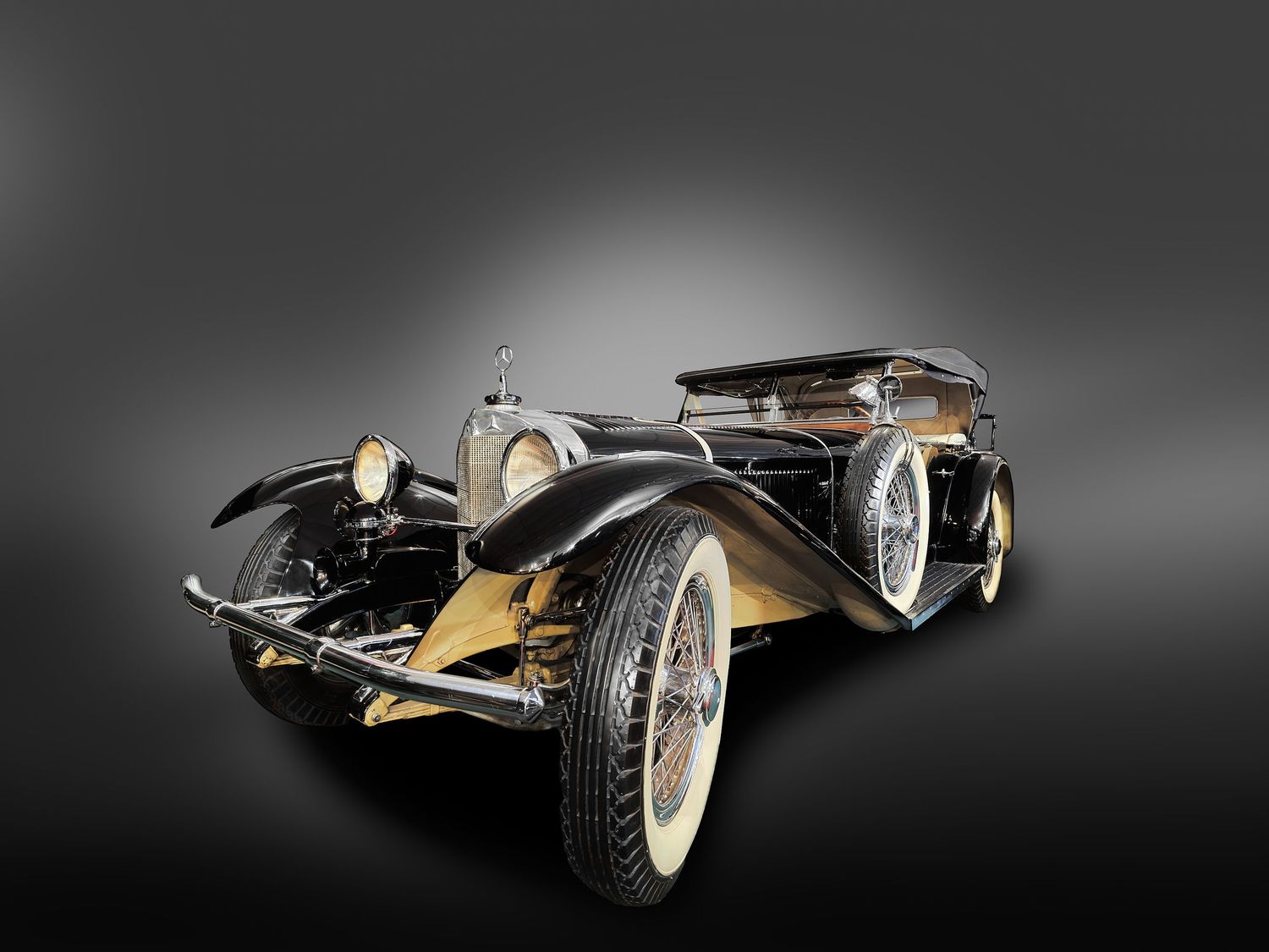 Vintage black and gold classic car with wire wheels on gradient gray background.