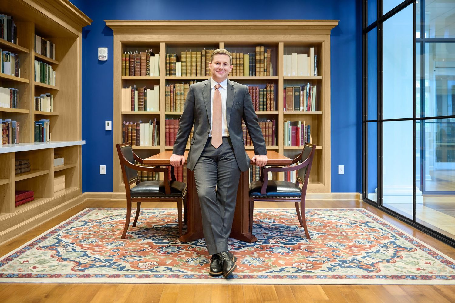 Professional man in suit posing confidently in elegant library setting.