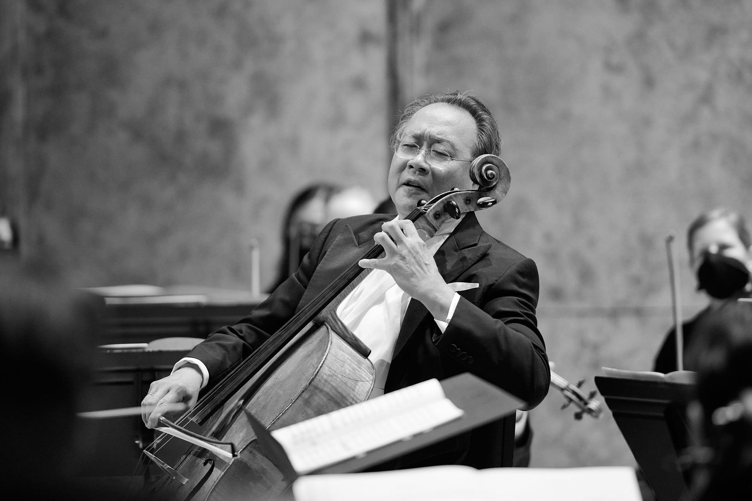 Musician playing cello passionately in black and white orchestra performance photo.