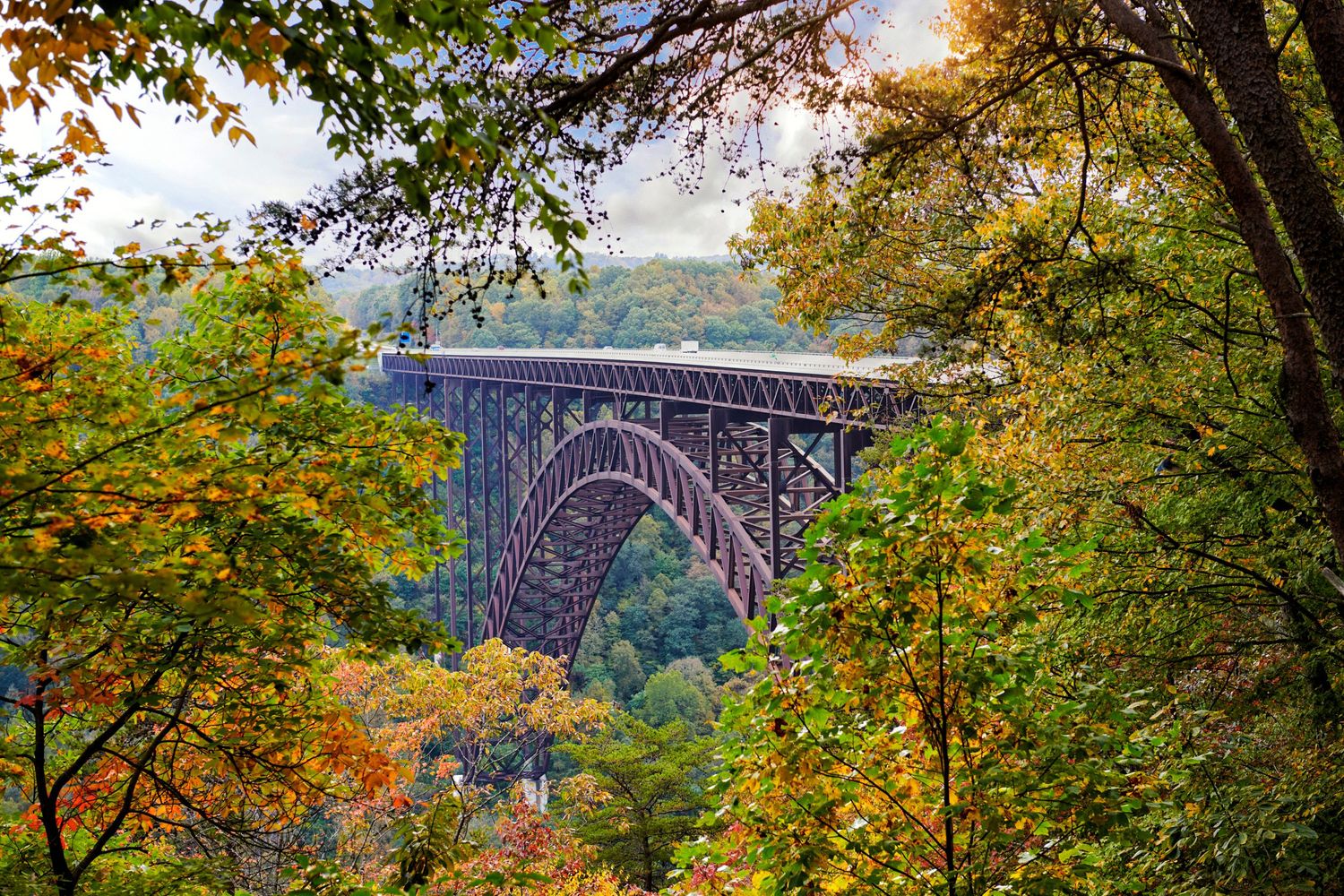New River Gorge steel arch bridge framed by vibrant autumn foliage in West Virginia.