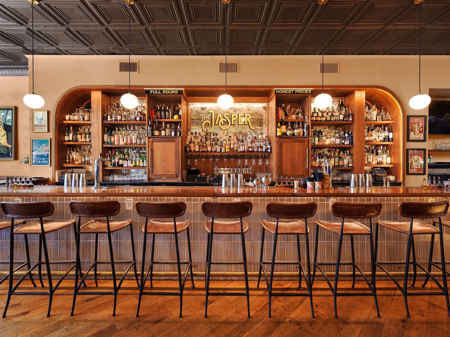 Classic bar interior with arched wood back bar, full liquor shelves, and row of metal bar stools.