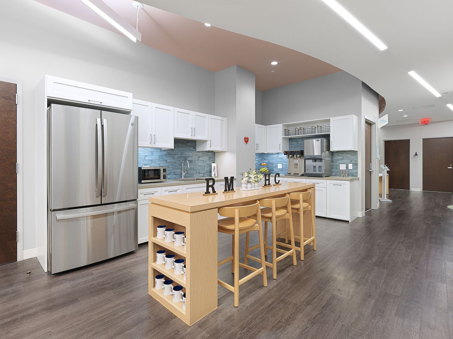Bright modern kitchen with white cabinets, stainless steel fridge, wood island, and bar stools.
