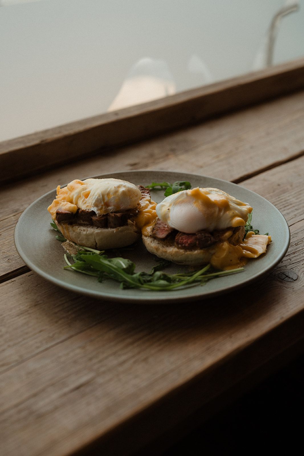 Eggs Benedict with poached eggs and hollandaise sauce on a plate on a wooden table.