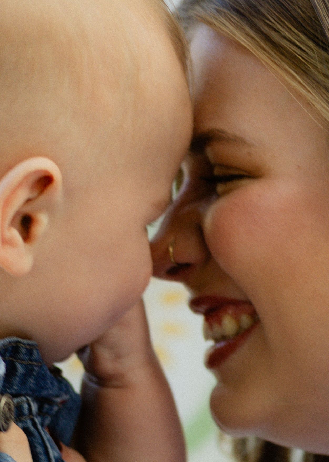 Close-up of a smiling mother touching foreheads with her baby in a tender bonding moment.