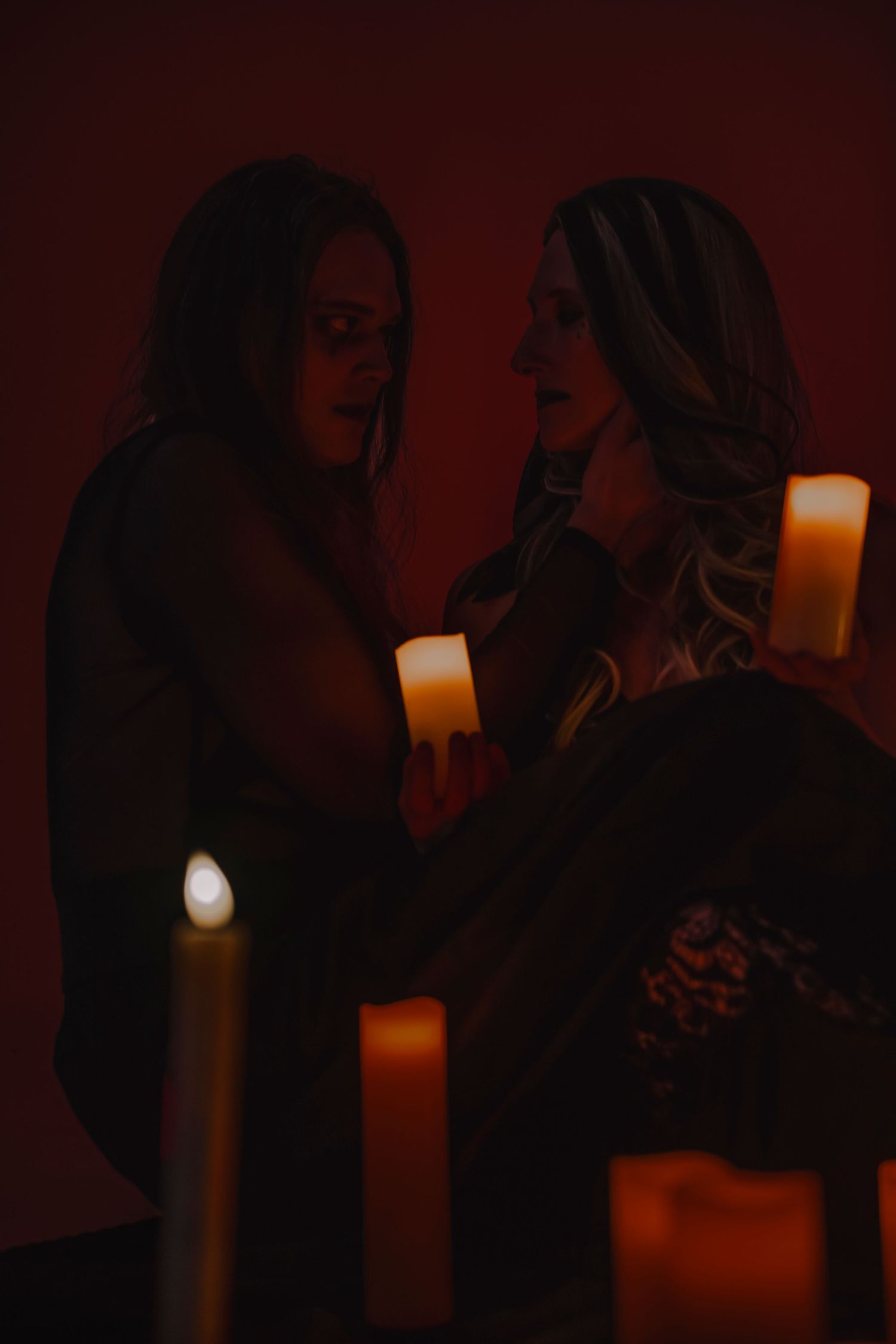 Silhouetted figures illuminated by candlelight create a dramatic and atmospheric scene in a dark room.