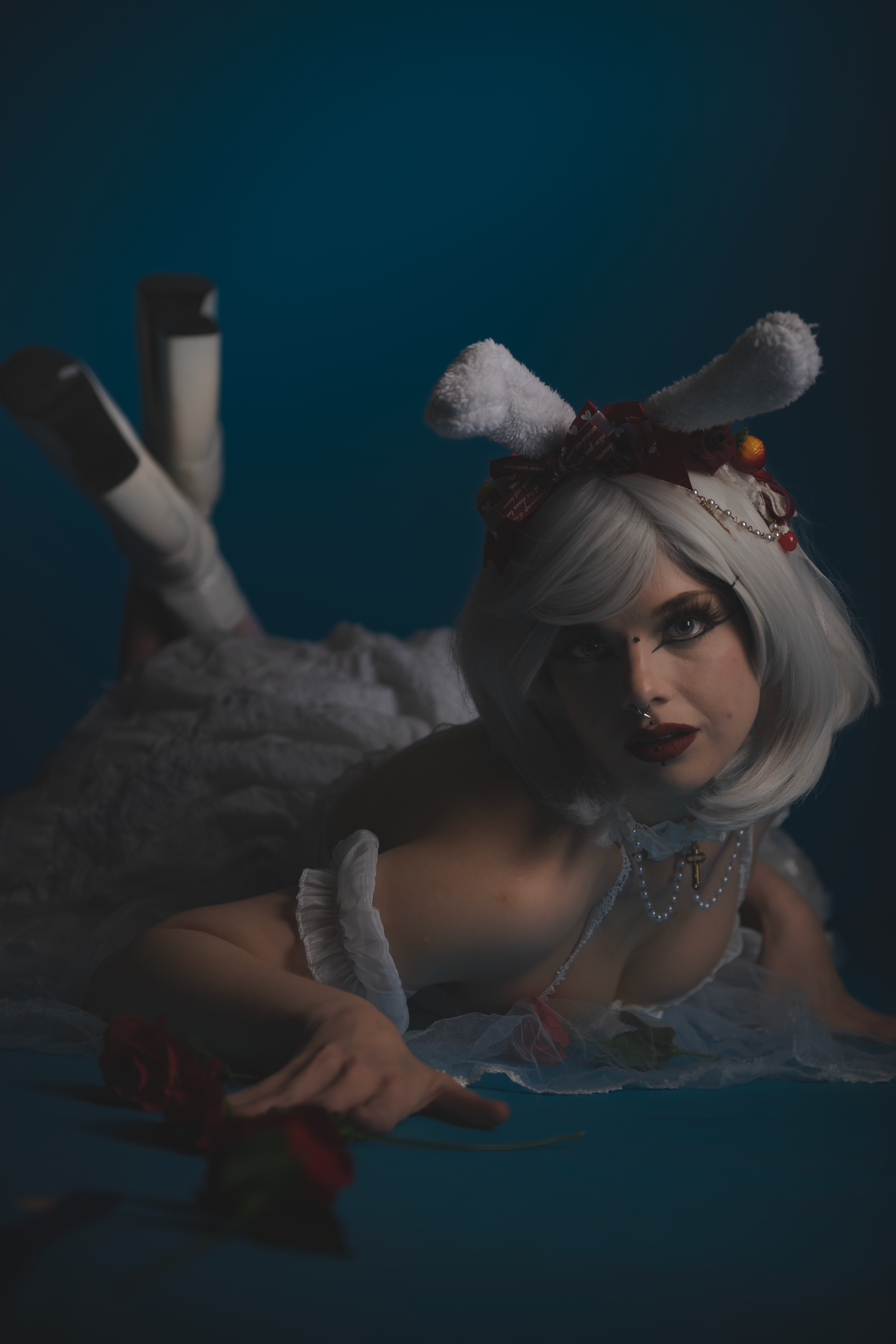 Gothic fashion shoot with white dress and roses in dramatic shadowy lighting.