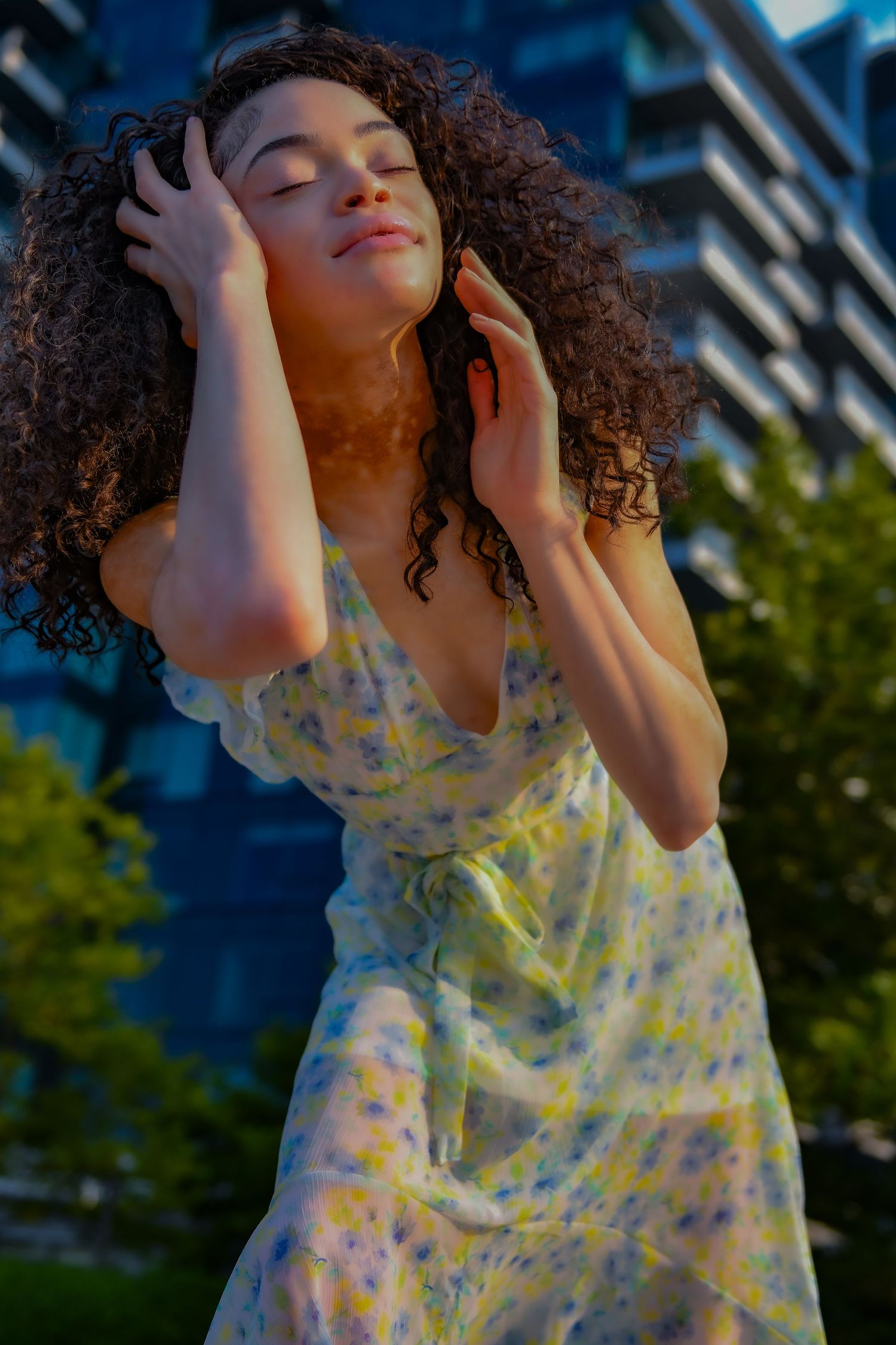 Dancing in a floral sundress with eyes closed at sunset.