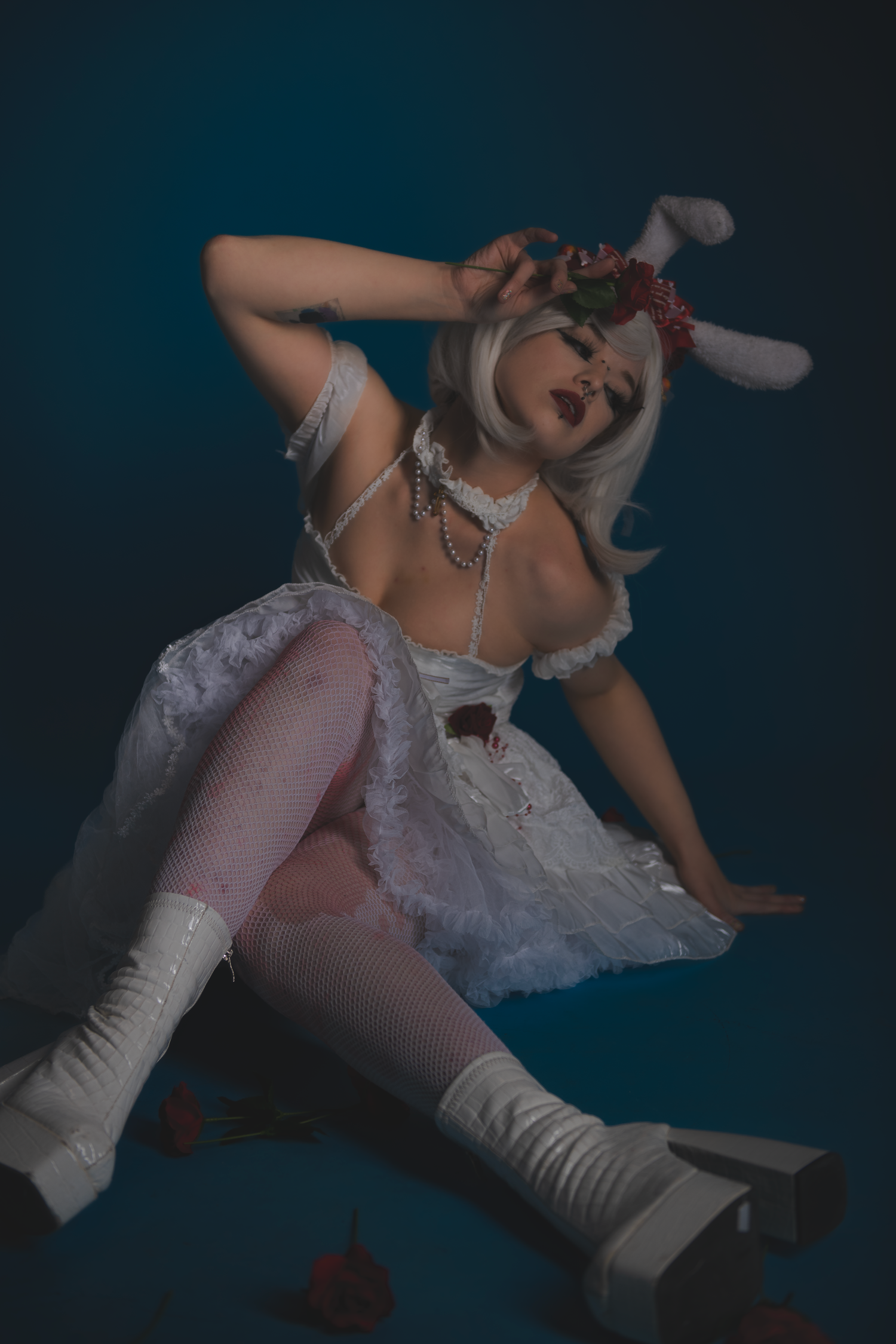 Dramatic fashion pose with white dress and boots on dark background.