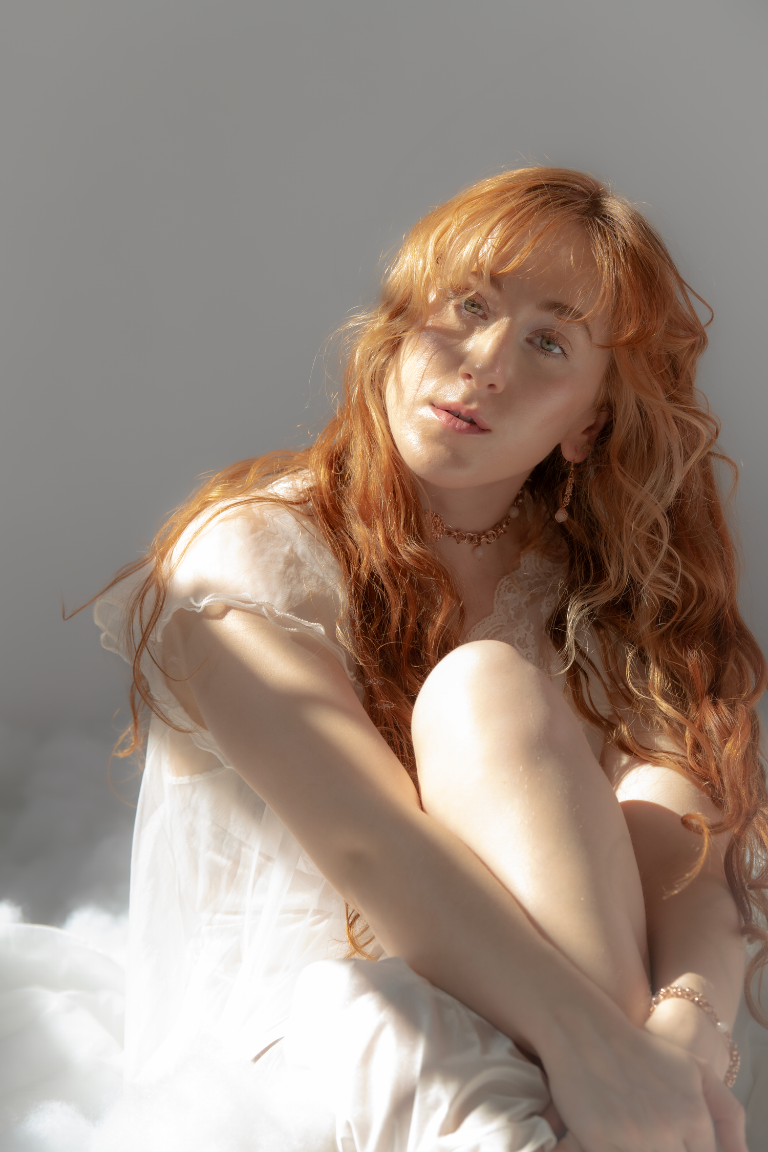 A series of artistic portraits showing flowing red hair and ethereal white fabric in dramatic natural lighting.