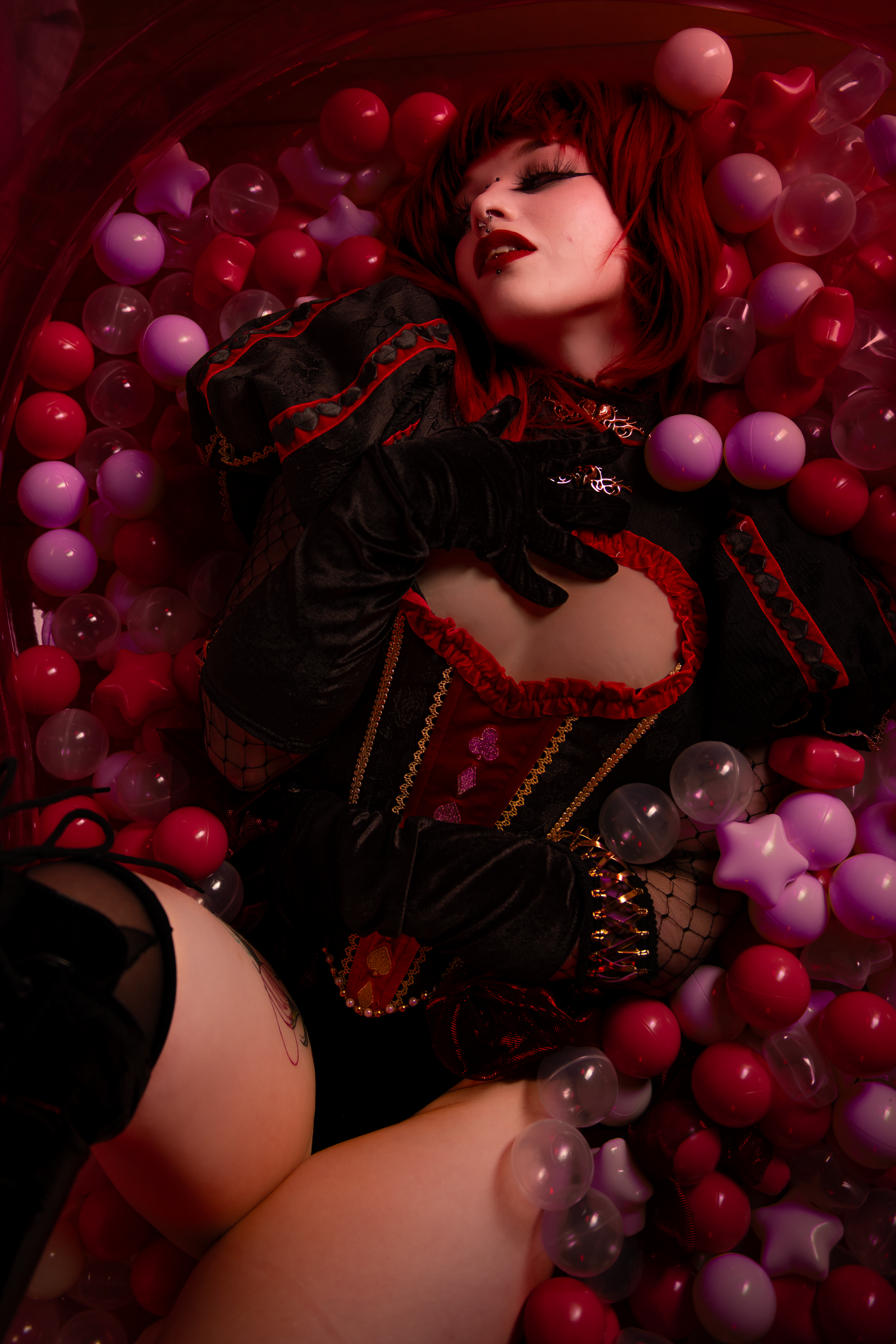 Atmospheric portrait surrounded by red and purple balloons with moody lighting and gothic fashion details.