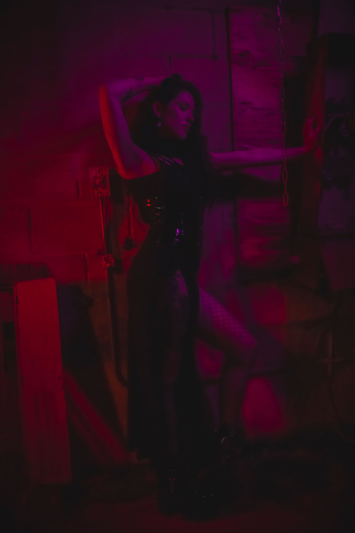Abstract dark and moody performance scene with dramatic red and purple lighting creating silhouettes on stage.