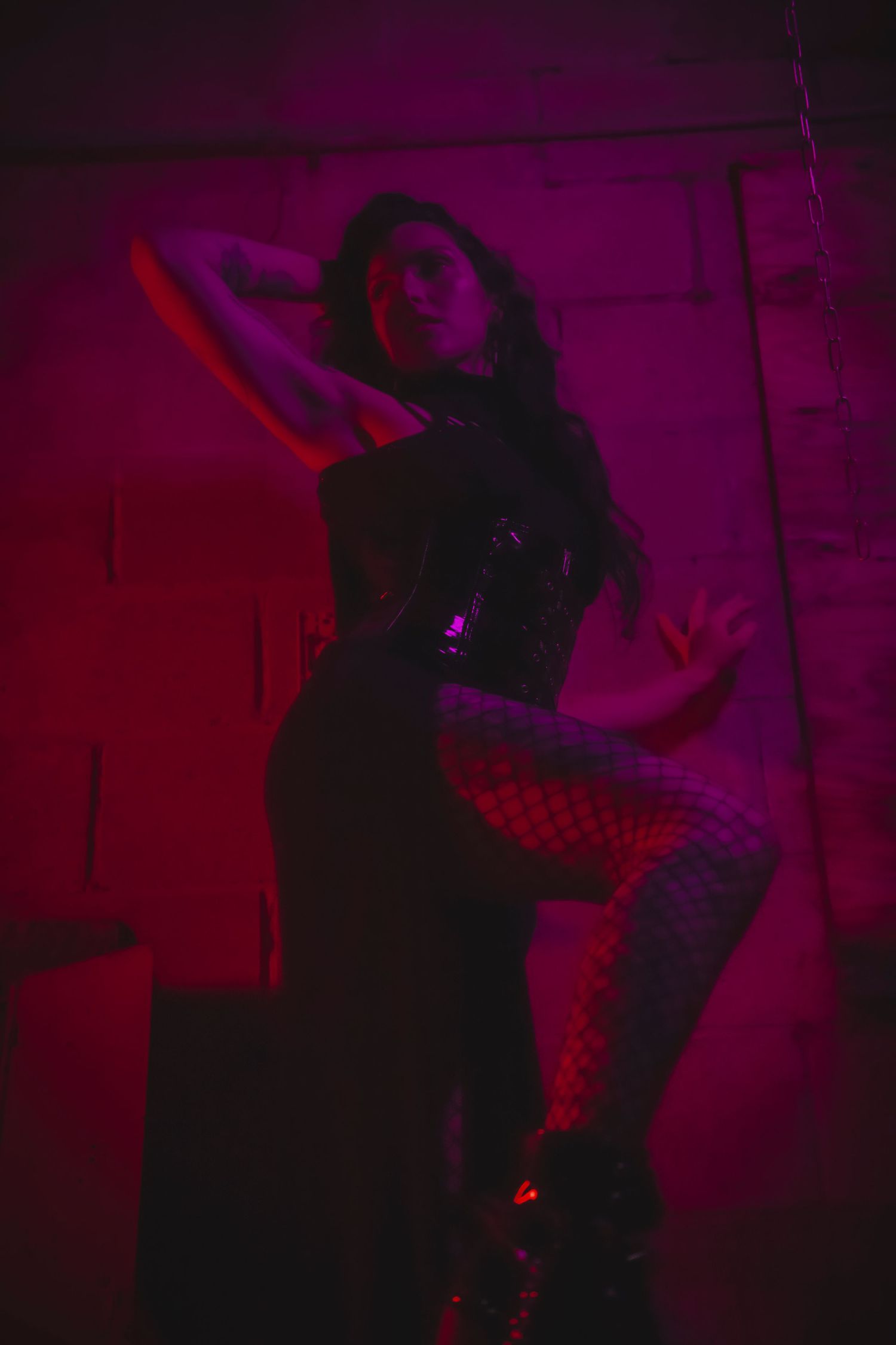 Performers move through a dimly lit space illuminated by deep purple and red stage lighting.