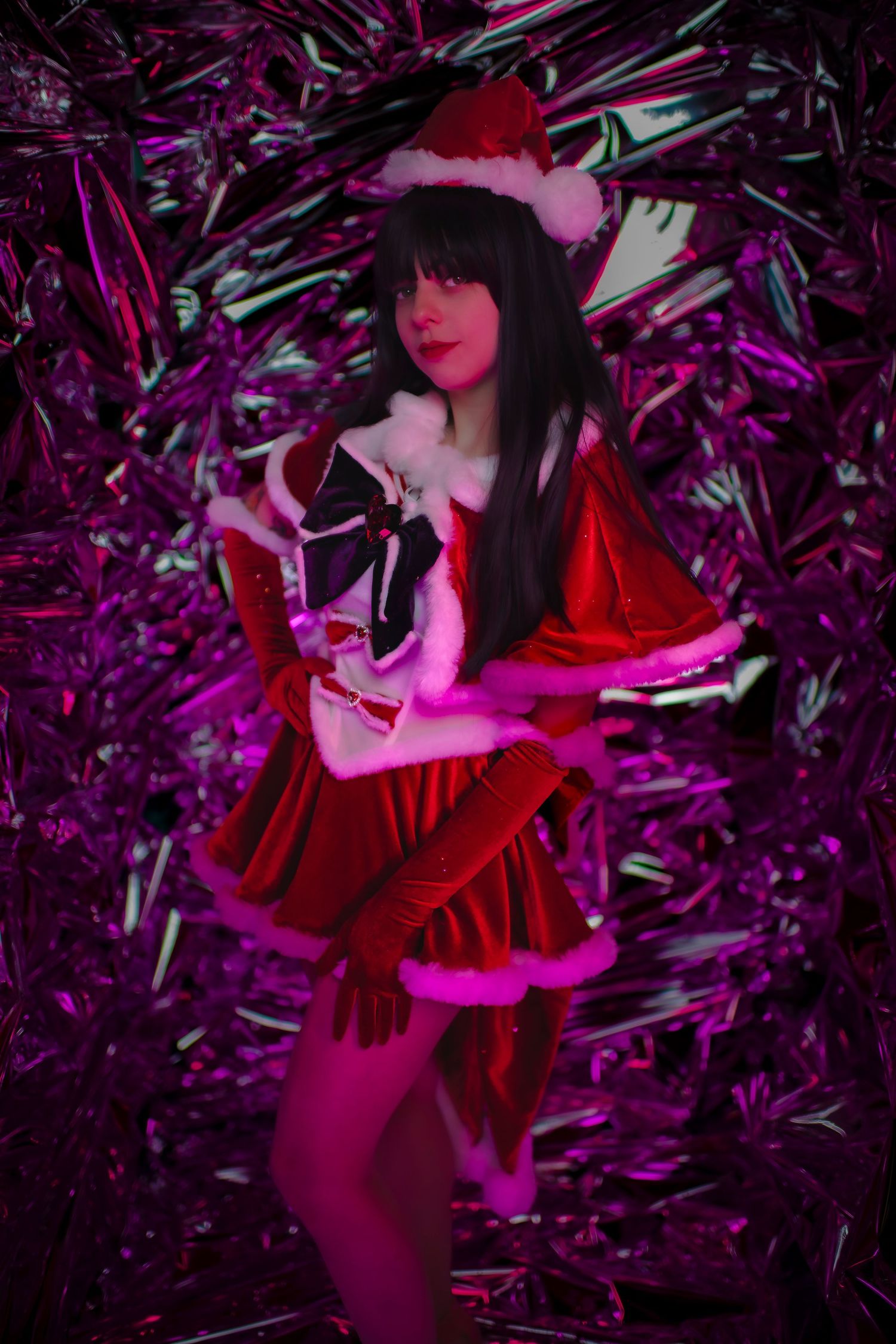 A Santa-themed holiday portrait against a purple tinsel background with dramatic neon colored lighting effects.