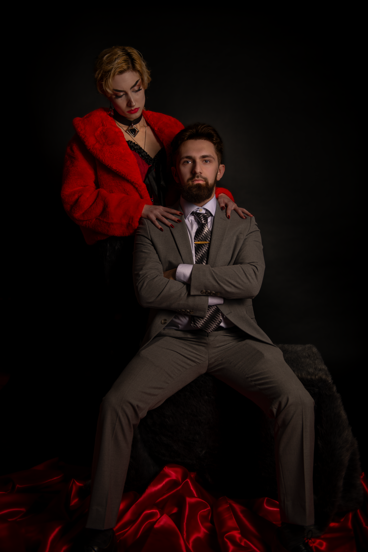 A dramatic studio portrait series against black background showing figures in grey suit and red coat in various poses.