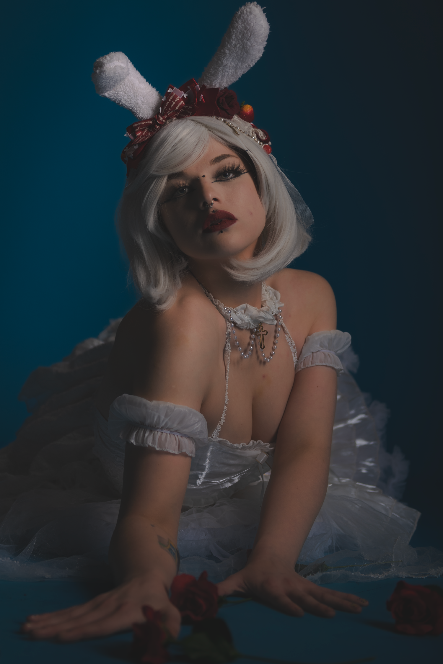 Ethereal photography featuring white dress and rose details against deep blue backdrop.