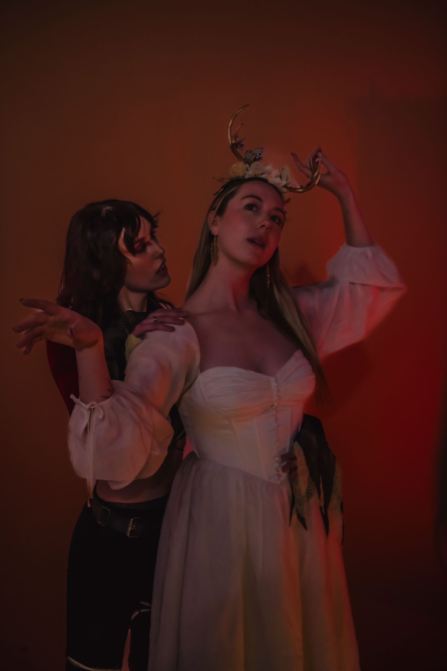 Performance art scene with dancers in white costumes against a moody red backdrop.