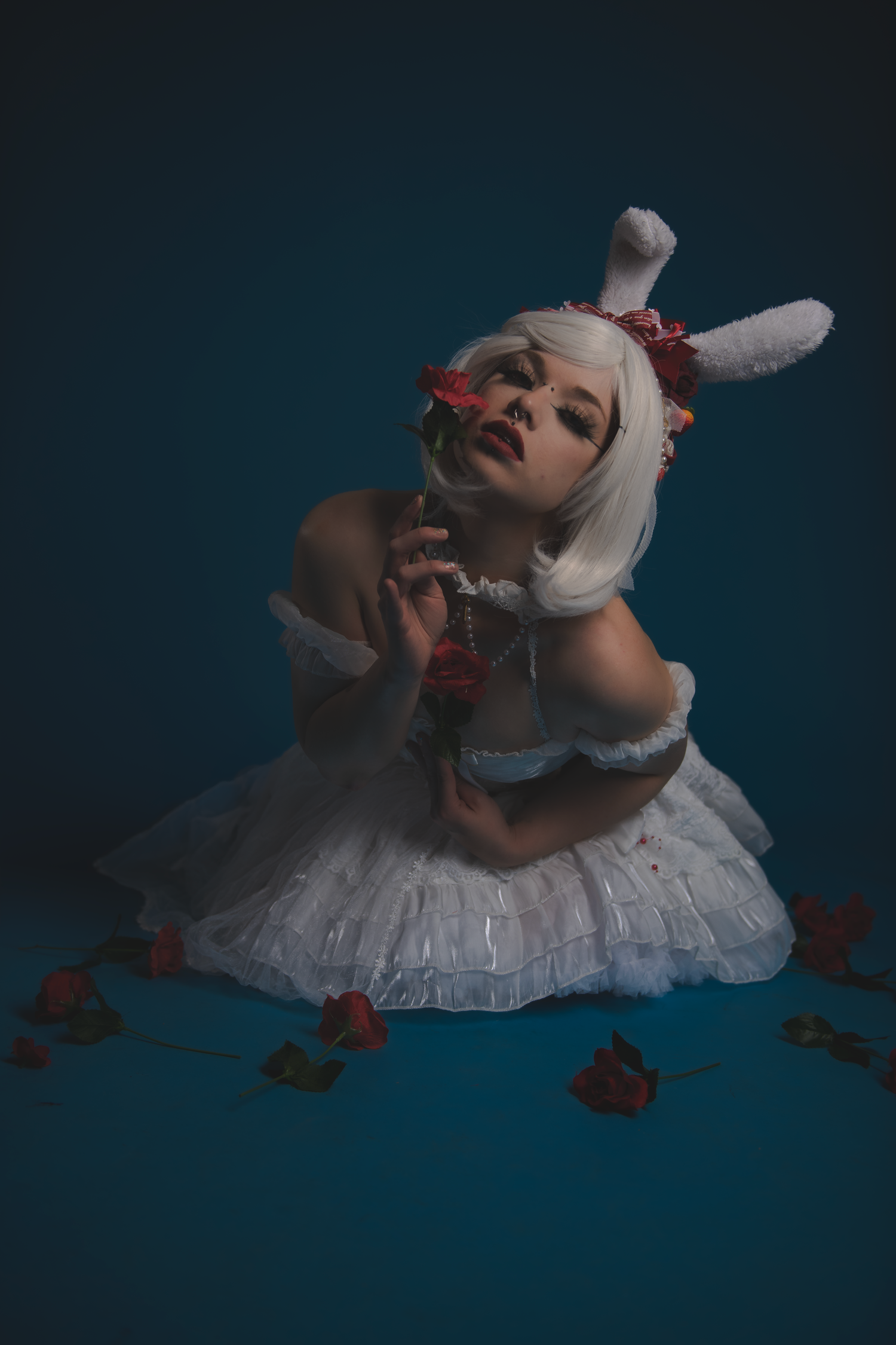 A series of artistic portraits showing a figure in white clothing lying on a dark blue background with scattered dried leaves.