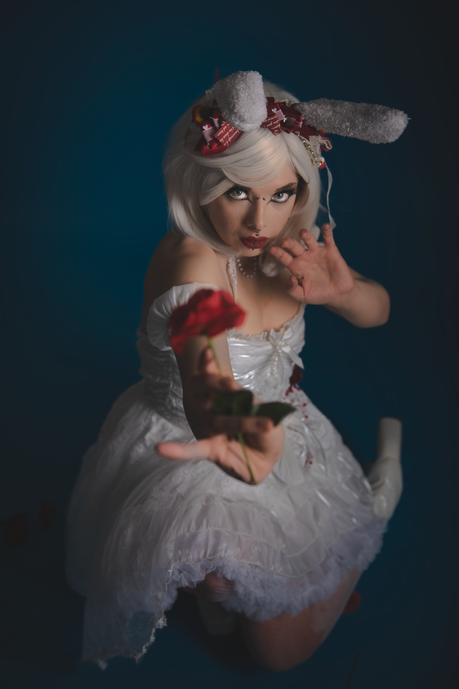 Artistic portrait featuring white dress and bunny ears in moody lighting.
