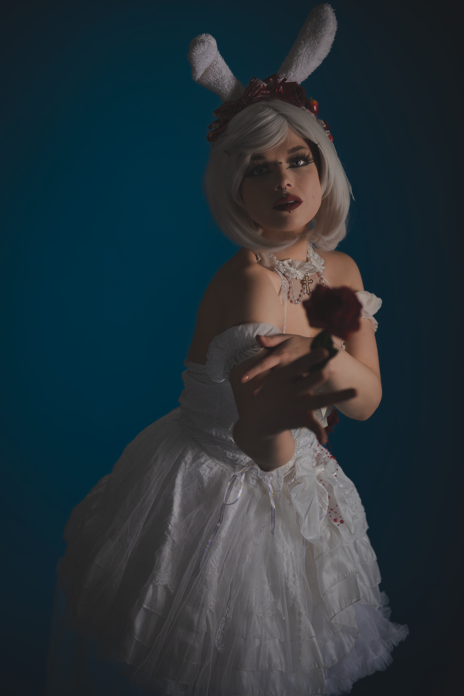 Moody portrait with white dress and rabbit ears in dramatic lighting.