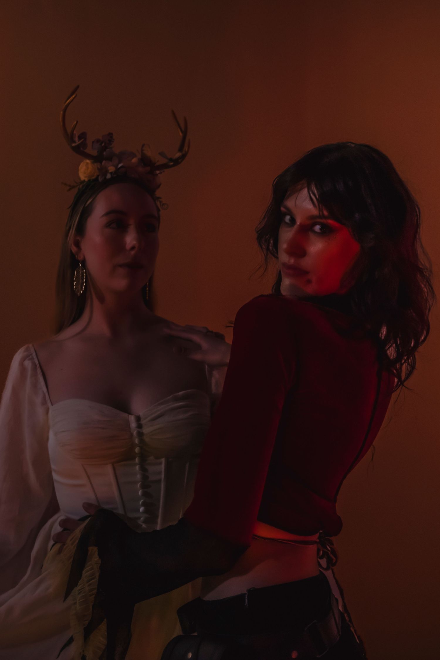 Dark artistic portrait series showing two individuals posing together in dramatic red lighting against brown backdrop.