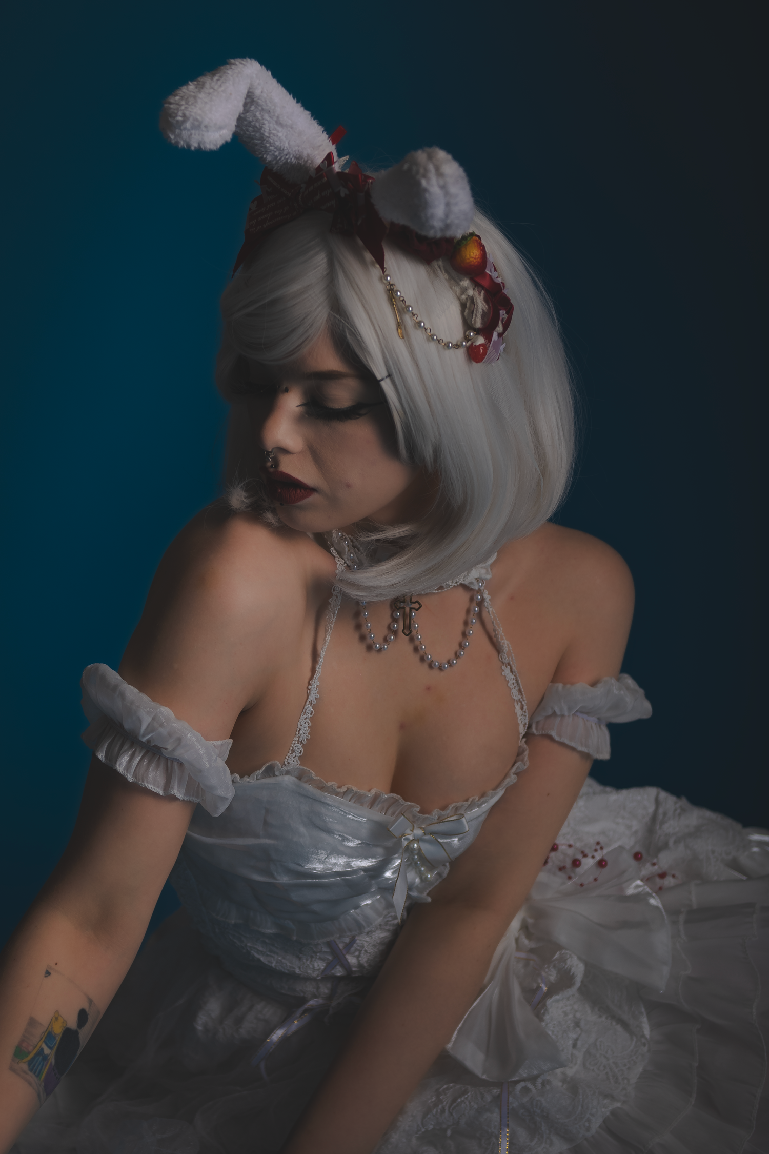 Ethereal cosplay featuring white dress and silver accessories in dim lighting.