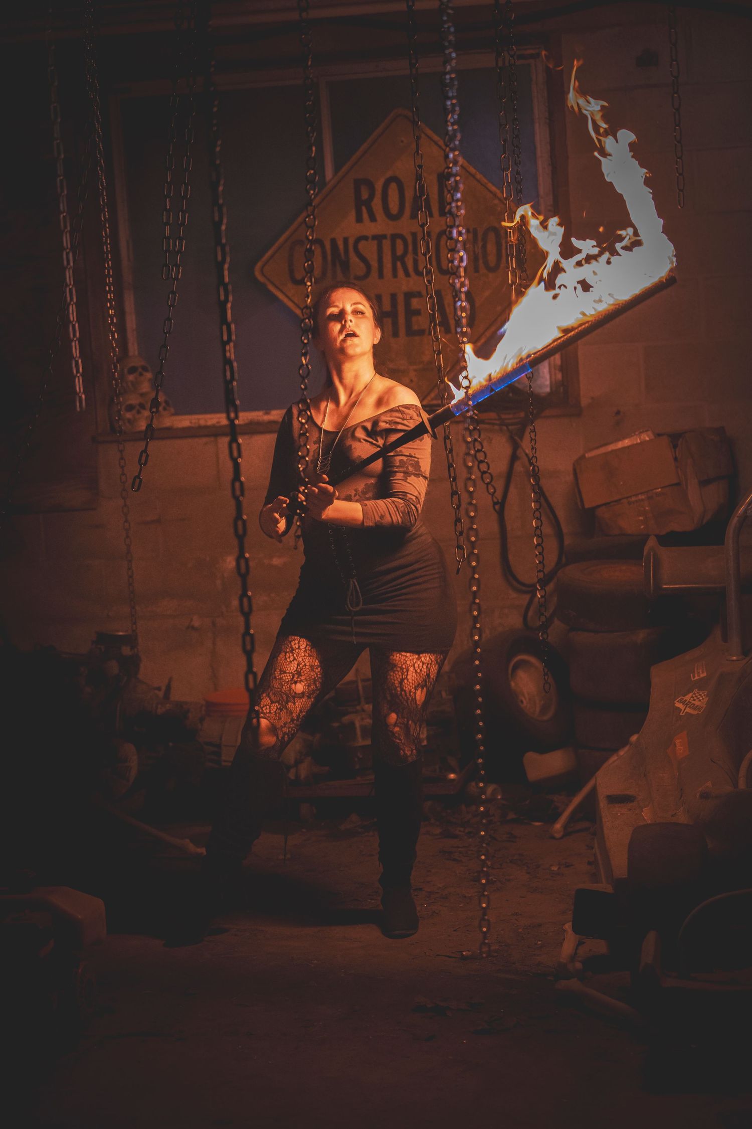 Fire performer spinning flames in a dark warehouse creating dramatic light trails and shadows.