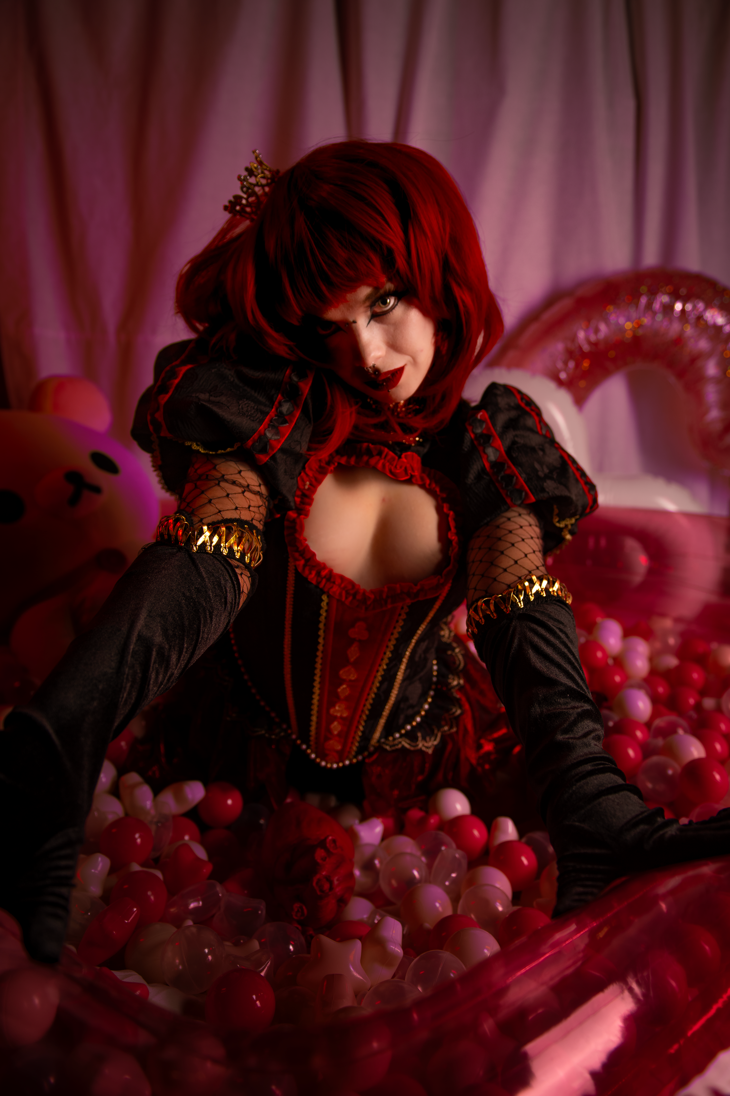 Stylized photoshoot against pink backdrop featuring gothic fashion elements and balloon decorations.