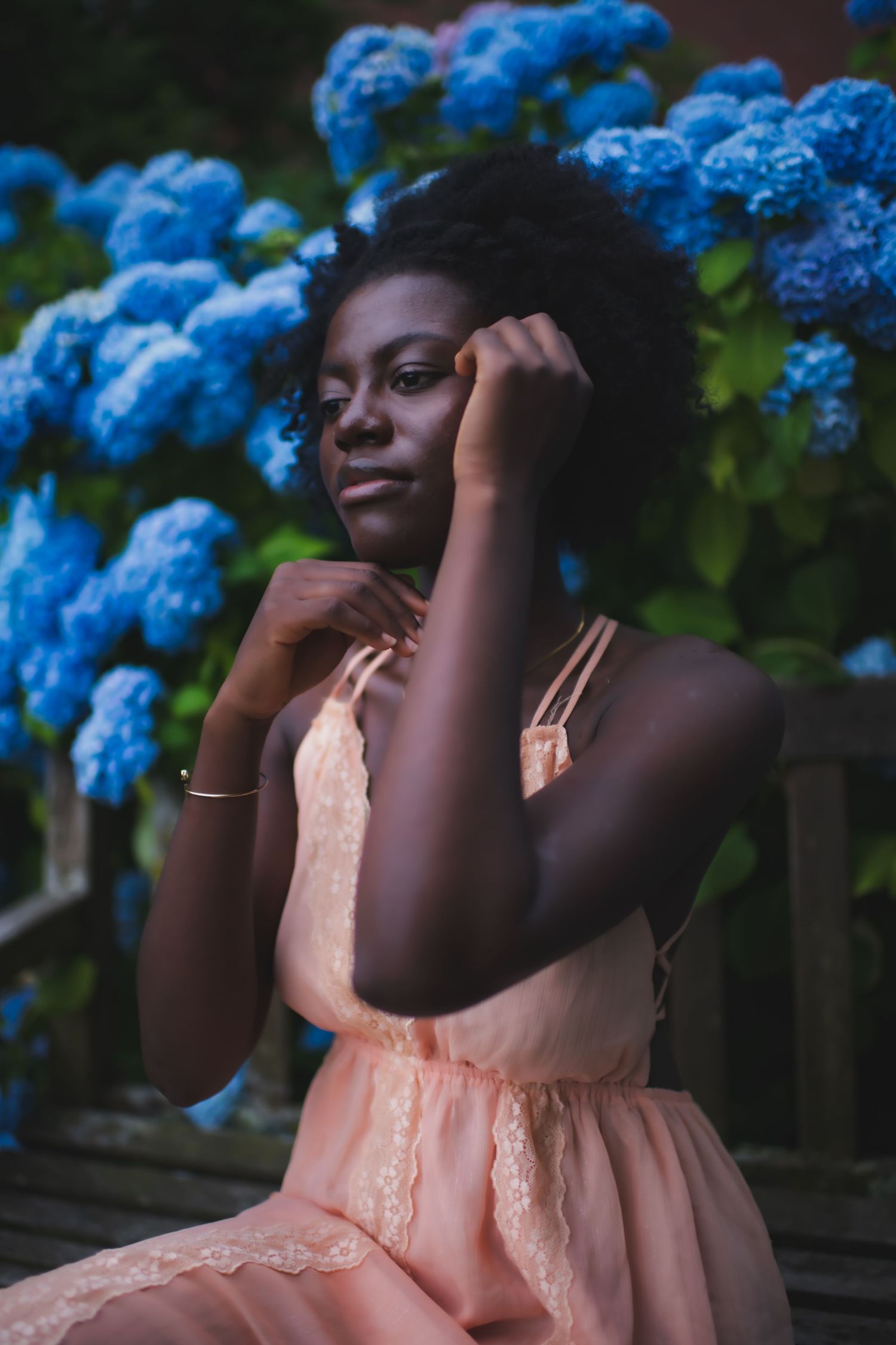 A dreamy portrait featuring soft peach tones against blue hydrangea blossoms.