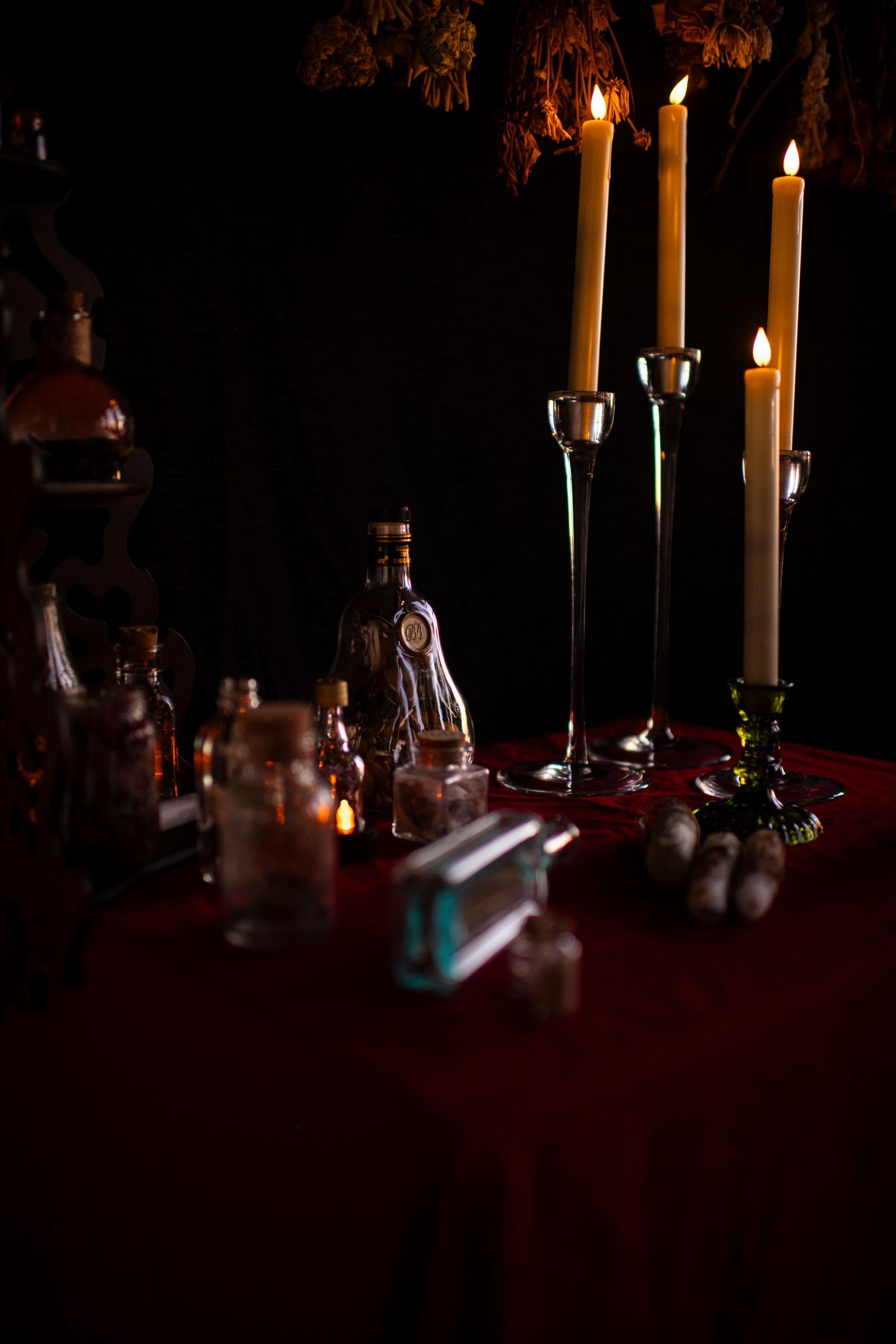 Glowing white candles create a warm ambiance on a dark table setting with holiday decorations.