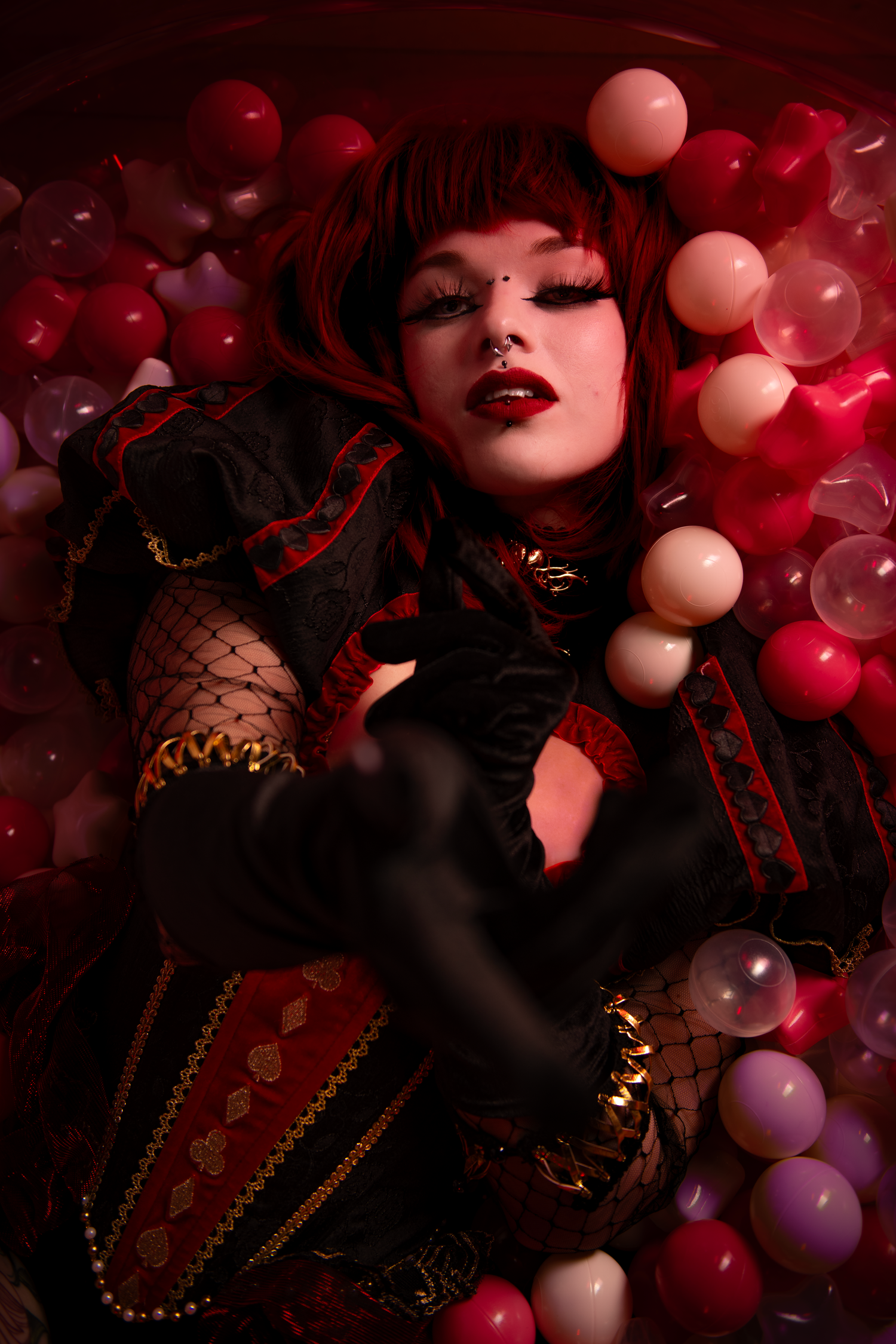 Artistic portrait with dramatic lighting surrounded by red and pink balloons in a dark gothic style.