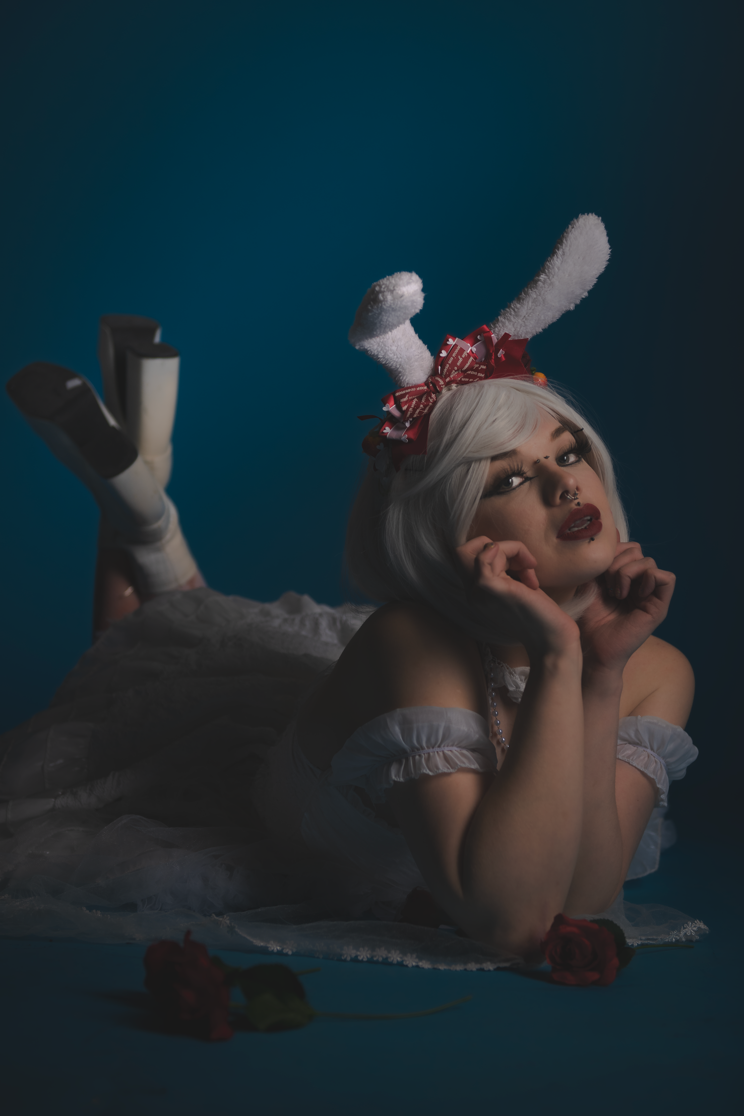 Dramatic cosplay portrait with white dress and dark makeup in moody lighting.