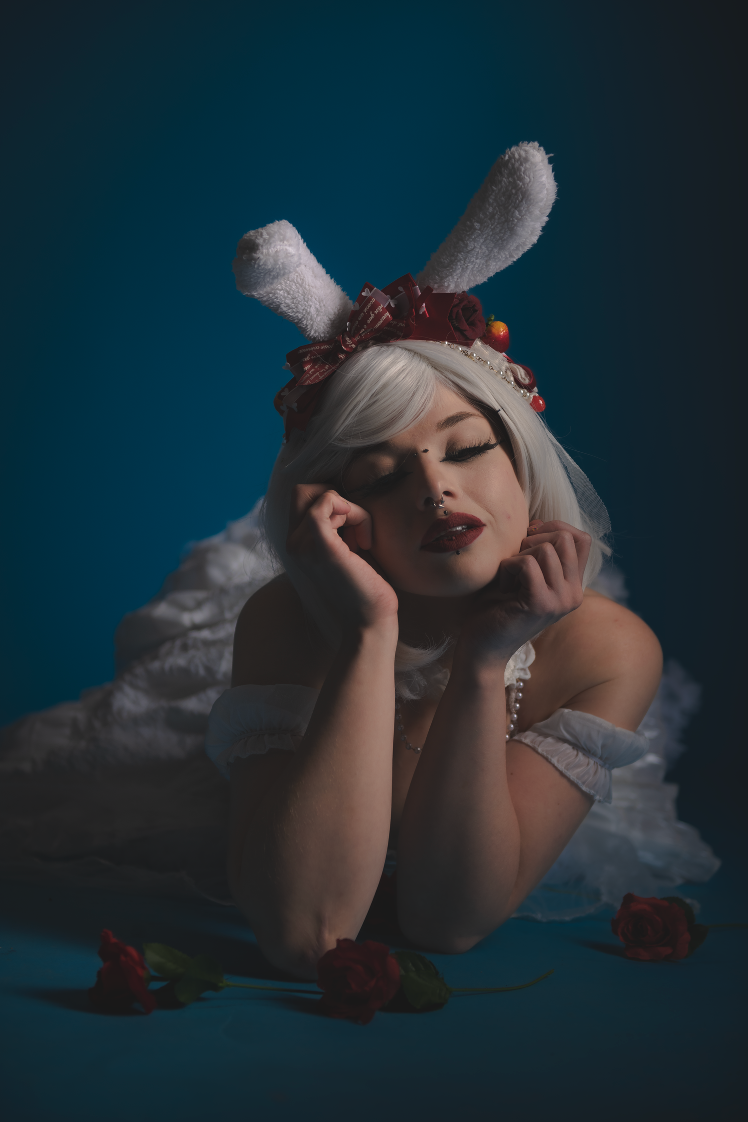 Artistic portrait featuring white dress and roses in moody lighting.