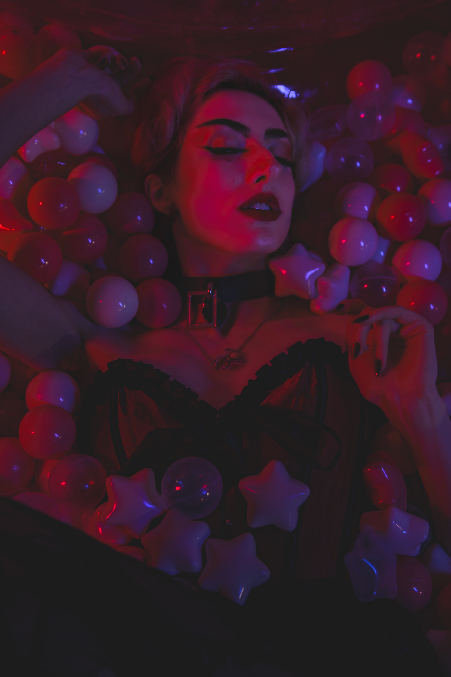 Several figures illuminated by vibrant red and blue lights dance in a dark nightclub atmosphere.
