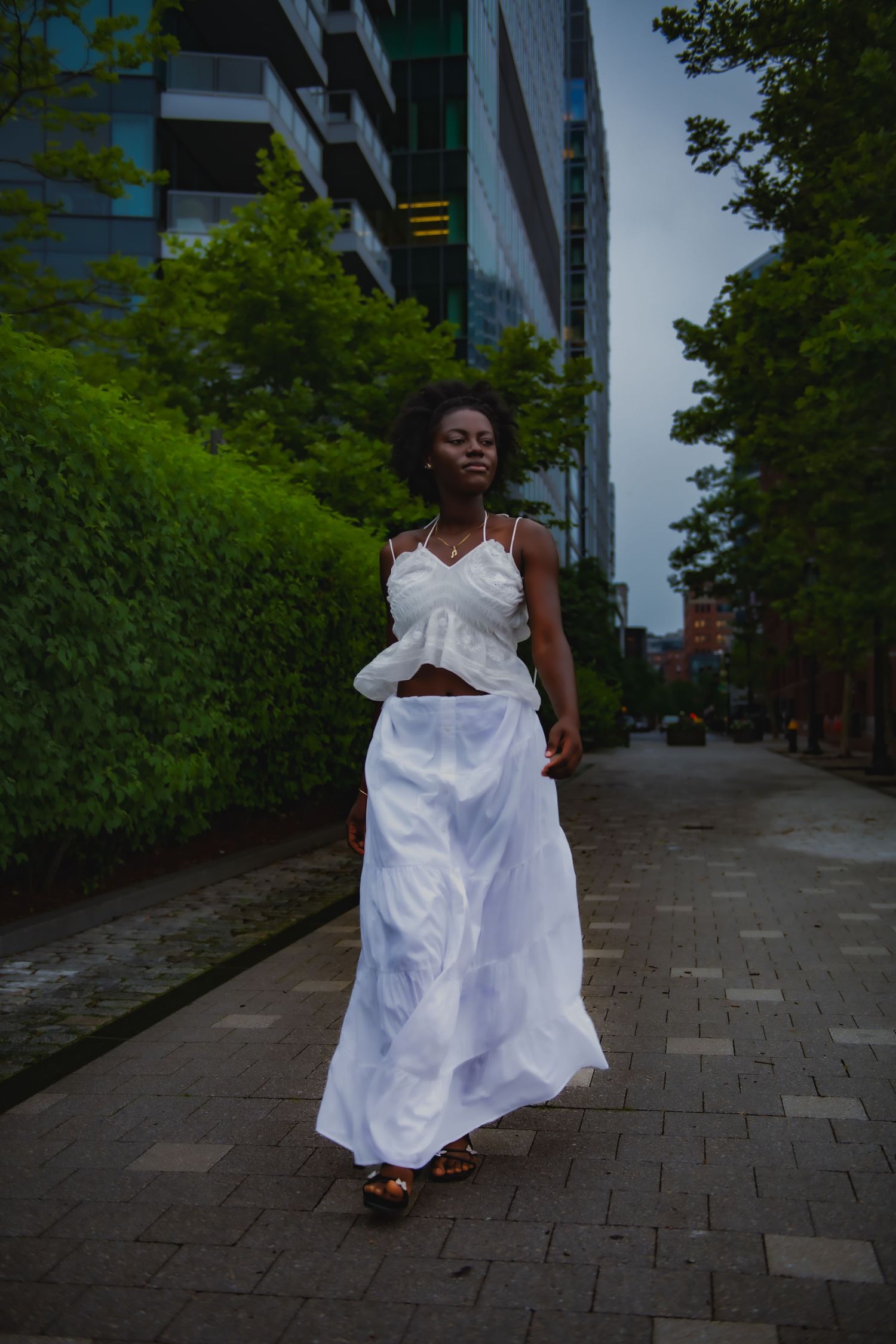 White two-piece ensemble walking along modern city sidewalk.