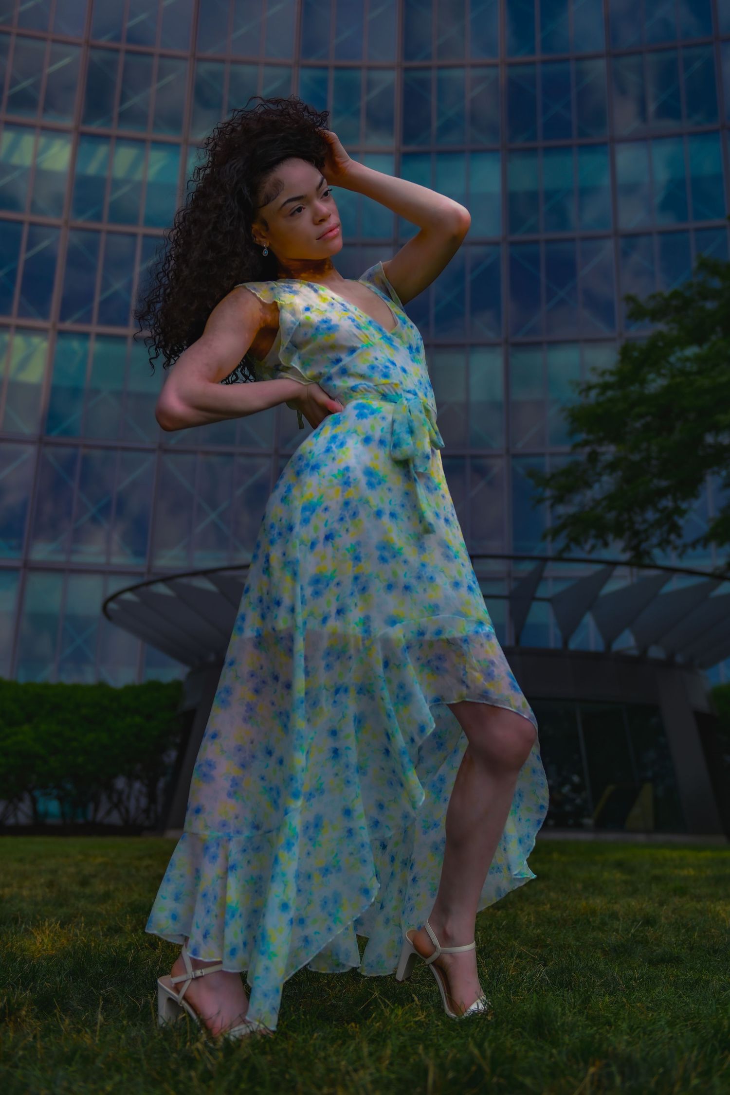 Floral dress photoshoot in an urban park setting with glass buildings in background.