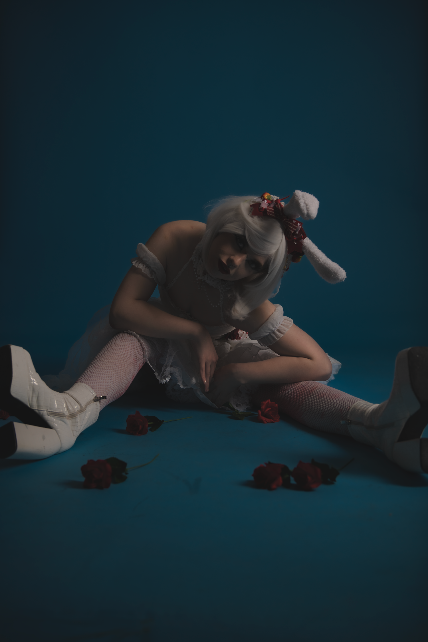 Dramatic low-light photo series with figure lying among scattered roses.