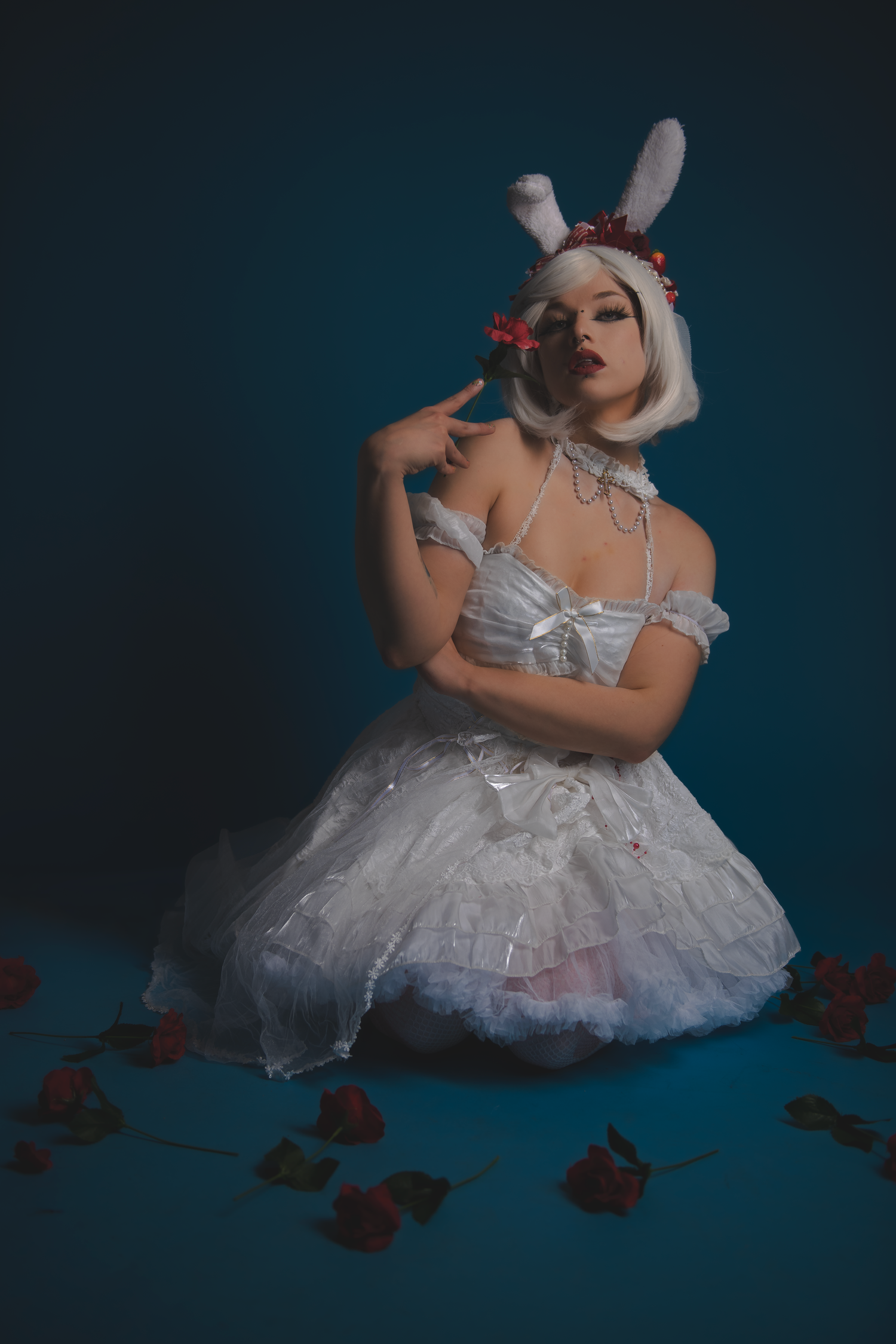 Artistic ballet-inspired photoshoot featuring white tulle dress and bunny ears against dark blue background with roses.