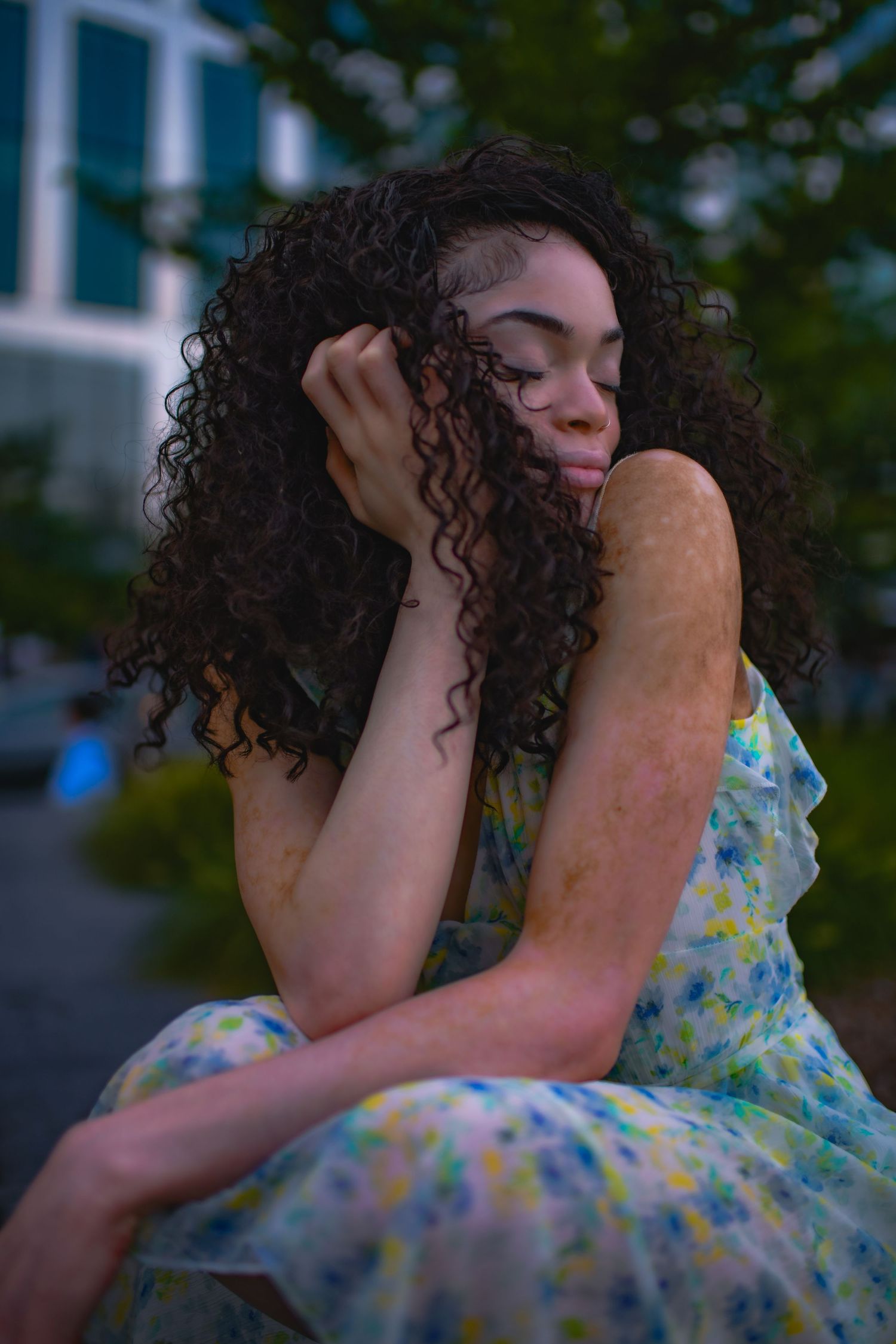 Dreamy pose in a blue floral dress against city backdrop.