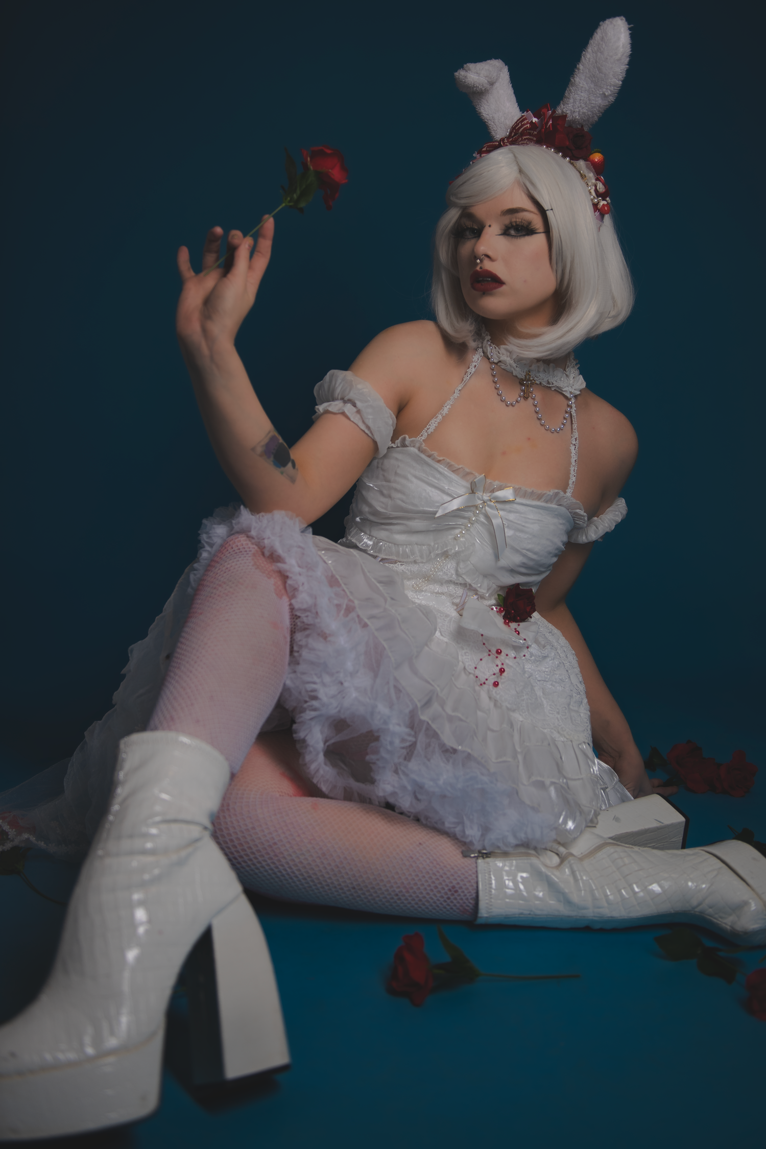 Gothic-inspired cosplay features white dress and platform boots against dark blue backdrop.