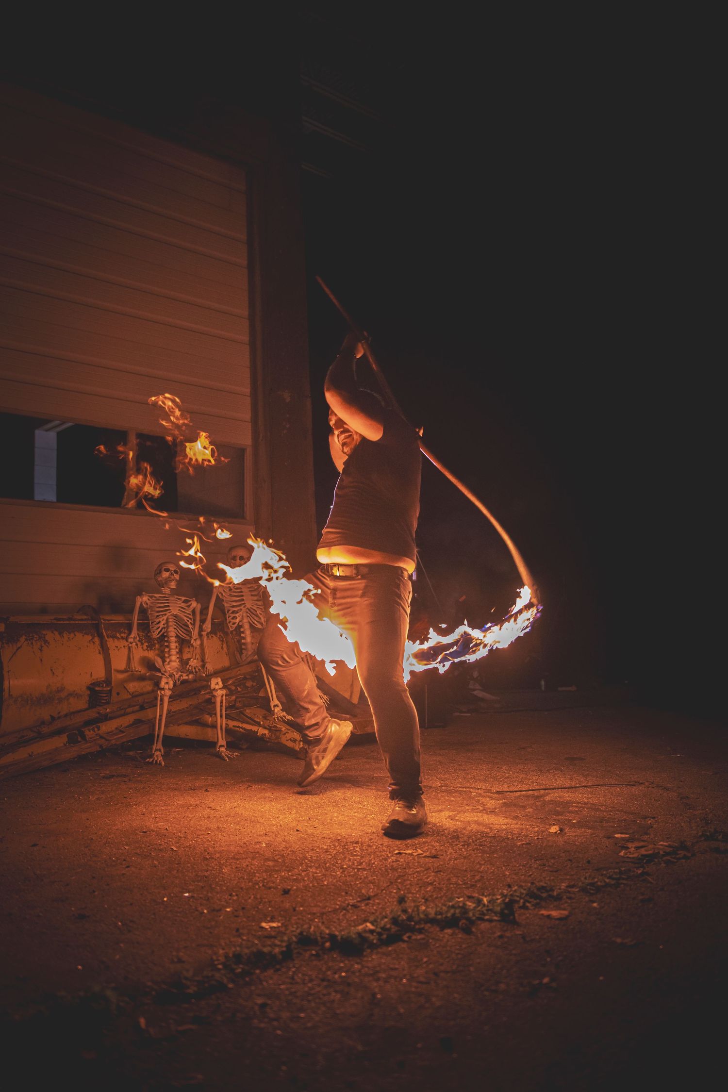 Fiery light trails swoop through the dark as a fire performer creates arcs of flame during a nighttime display.