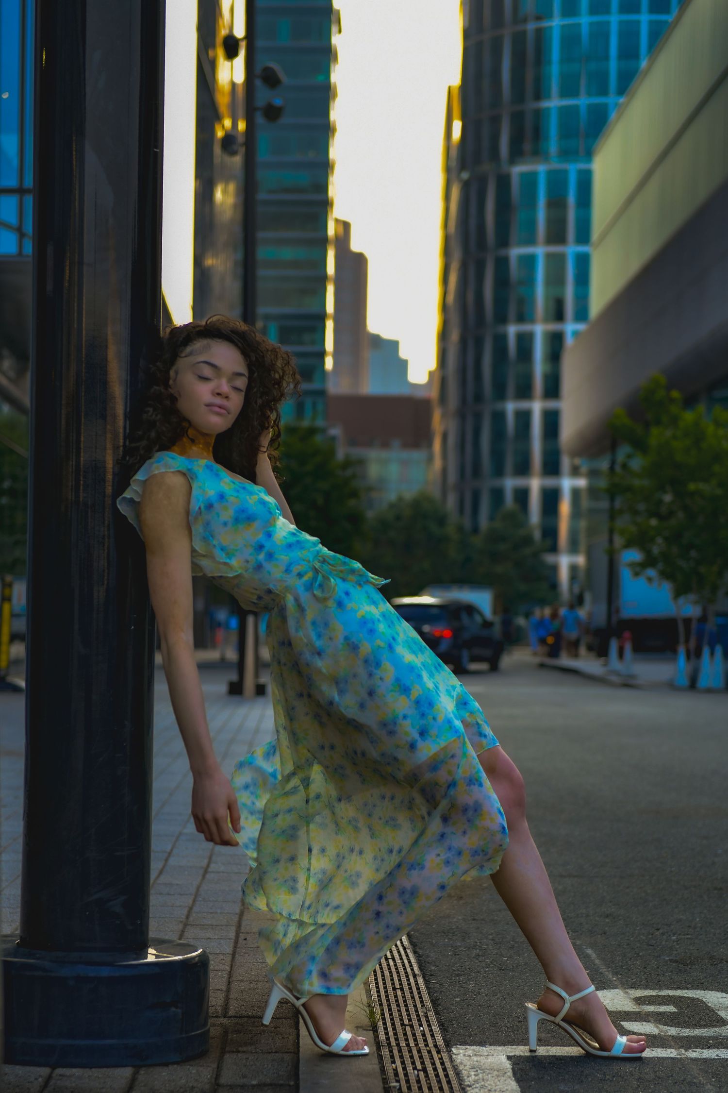Urban fashion photo featuring a floral dress against city buildings at dusk.