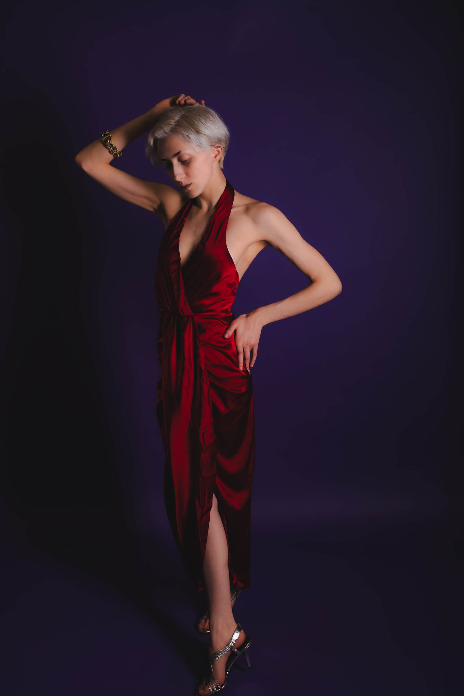 A figure in a flowing red dress strikes dramatic dance poses against a dark purple background.