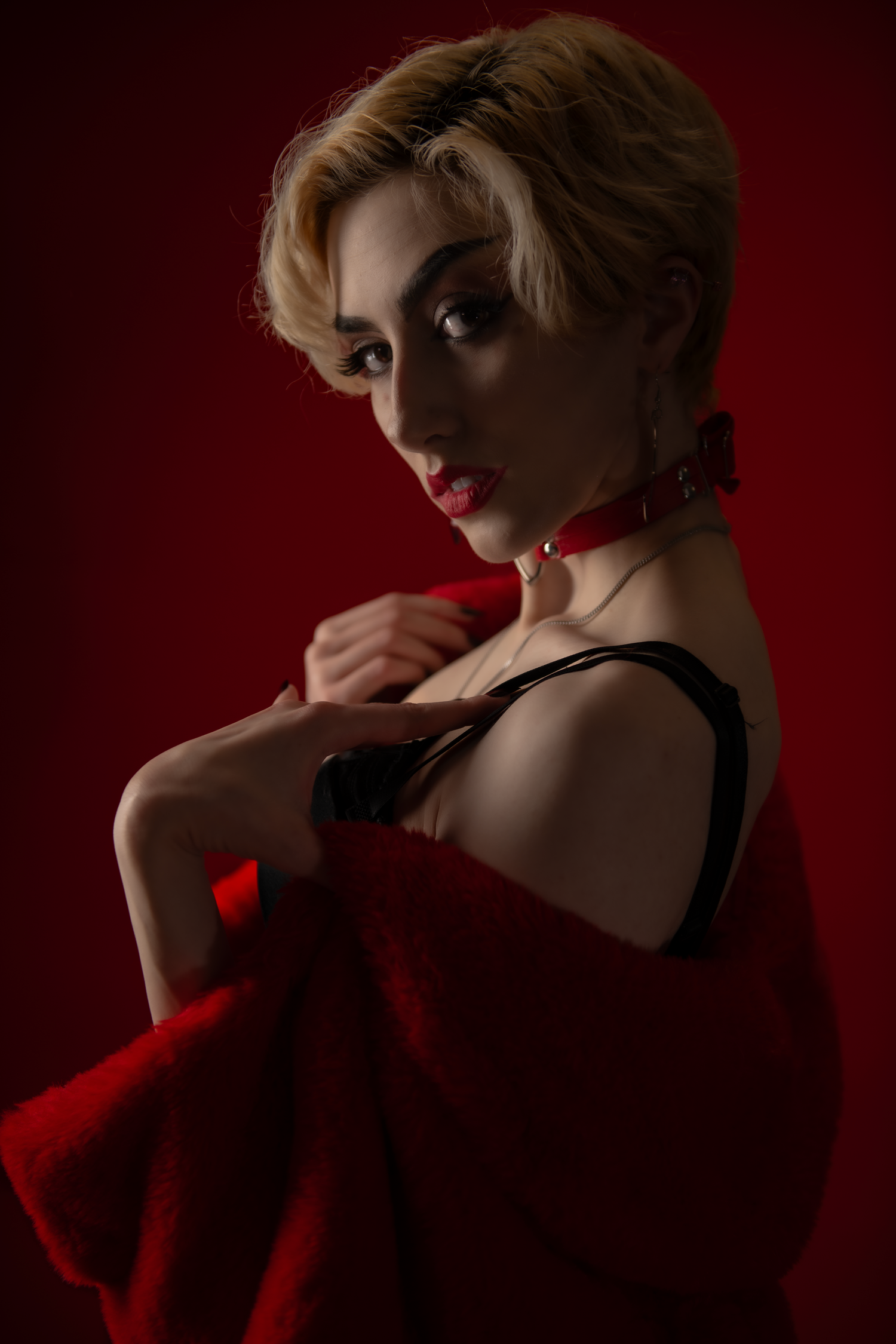 Dramatic fashion portraits on deep red background featuring blonde hair and bold red fabric styling in moody lighting.