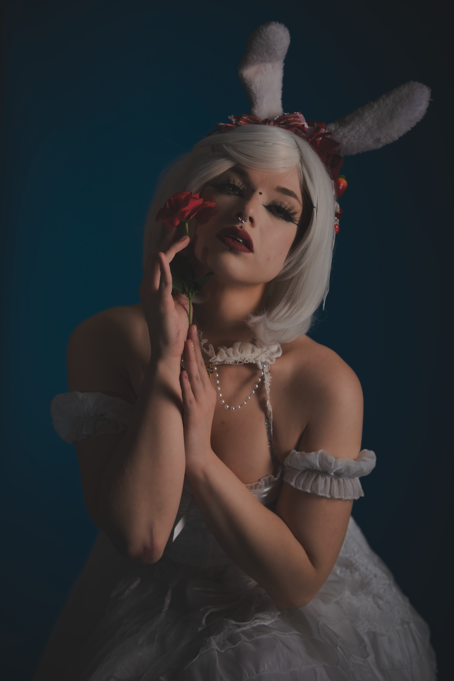 Artistic portrait featuring model in white dress and bunny ears with dramatic side lighting.