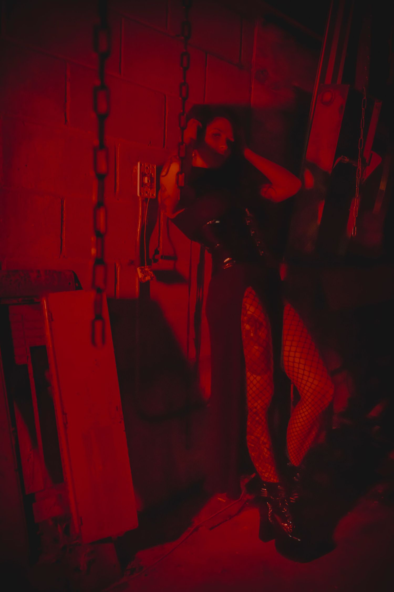 Dark silhouettes dance in a nightclub bathed in dramatic red lighting with atmospheric smoke effects.