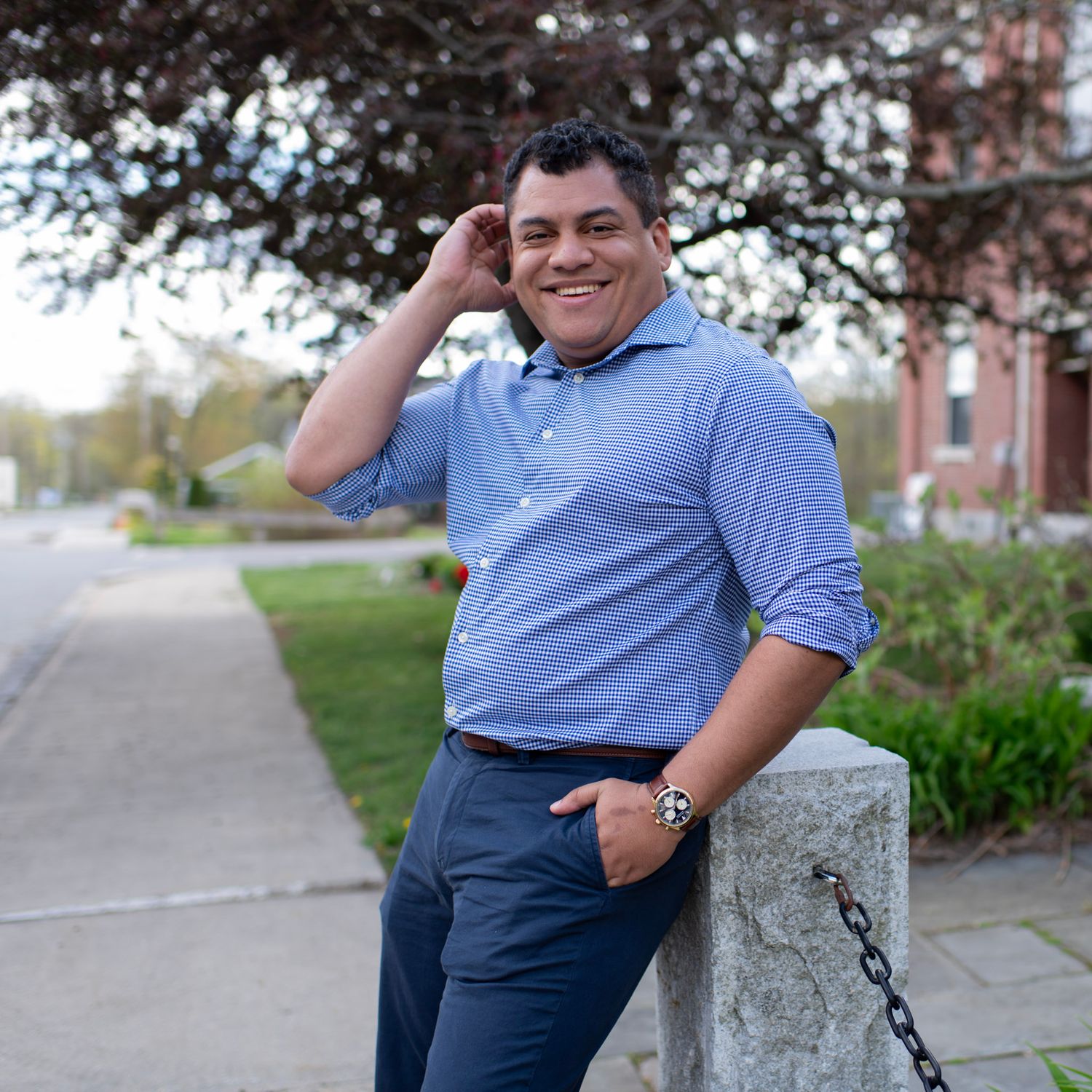 Casual outdoor portrait leaning on stone pillar wearing business attire.
