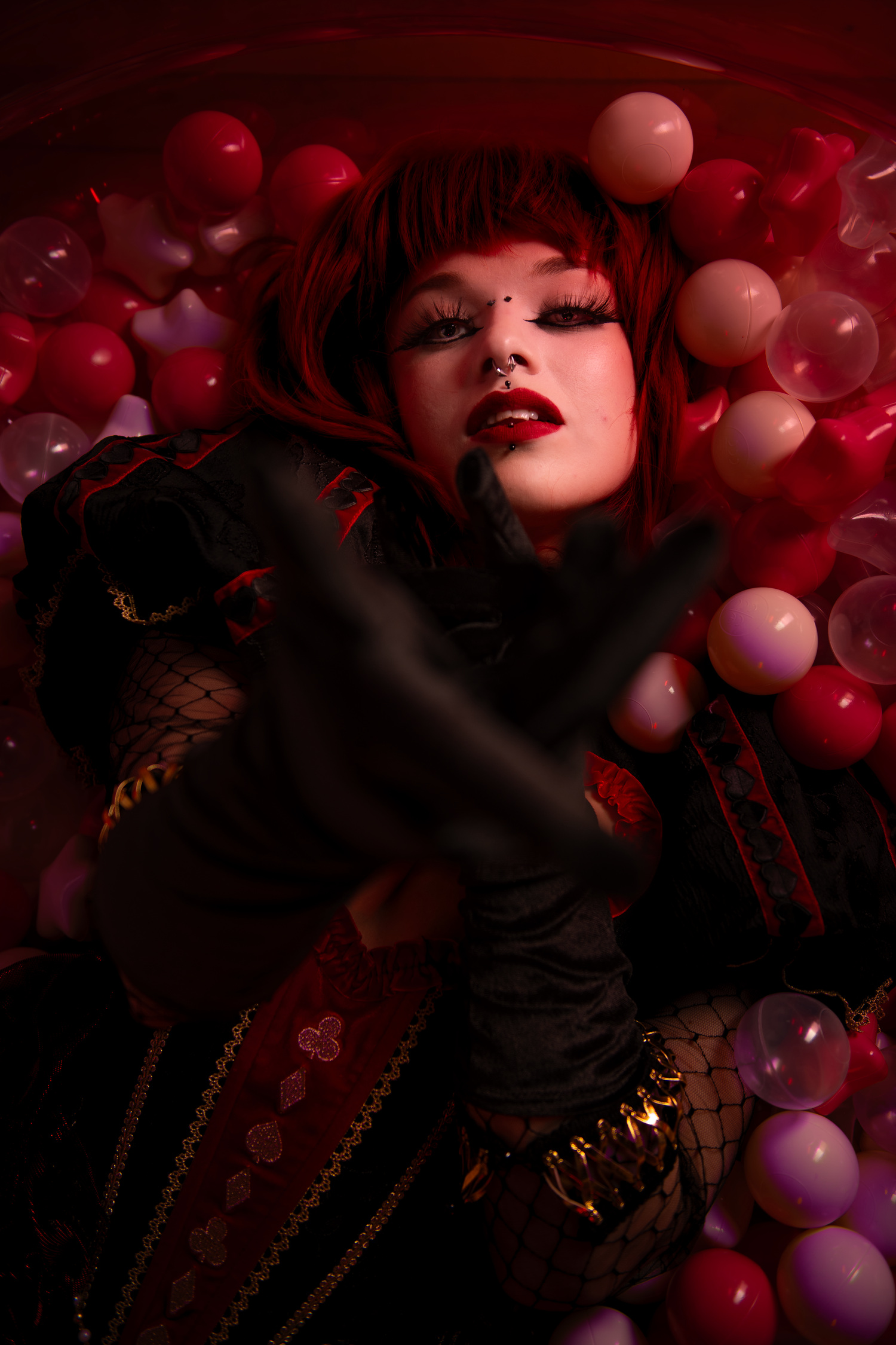 Dark moody photo with red and pink balloons floating around dramatic lighting and shadows in club atmosphere.
